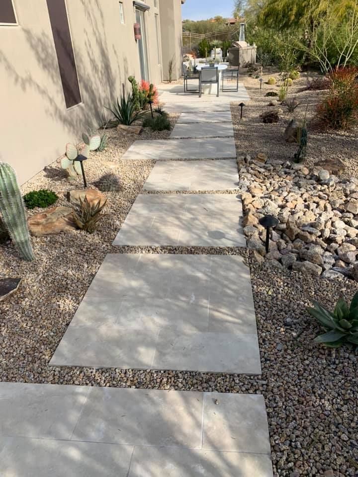 A stone walkway leading to a house with rocks and plants.