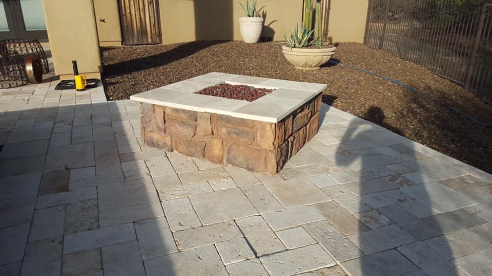 A fire pit is sitting on a patio next to a house.