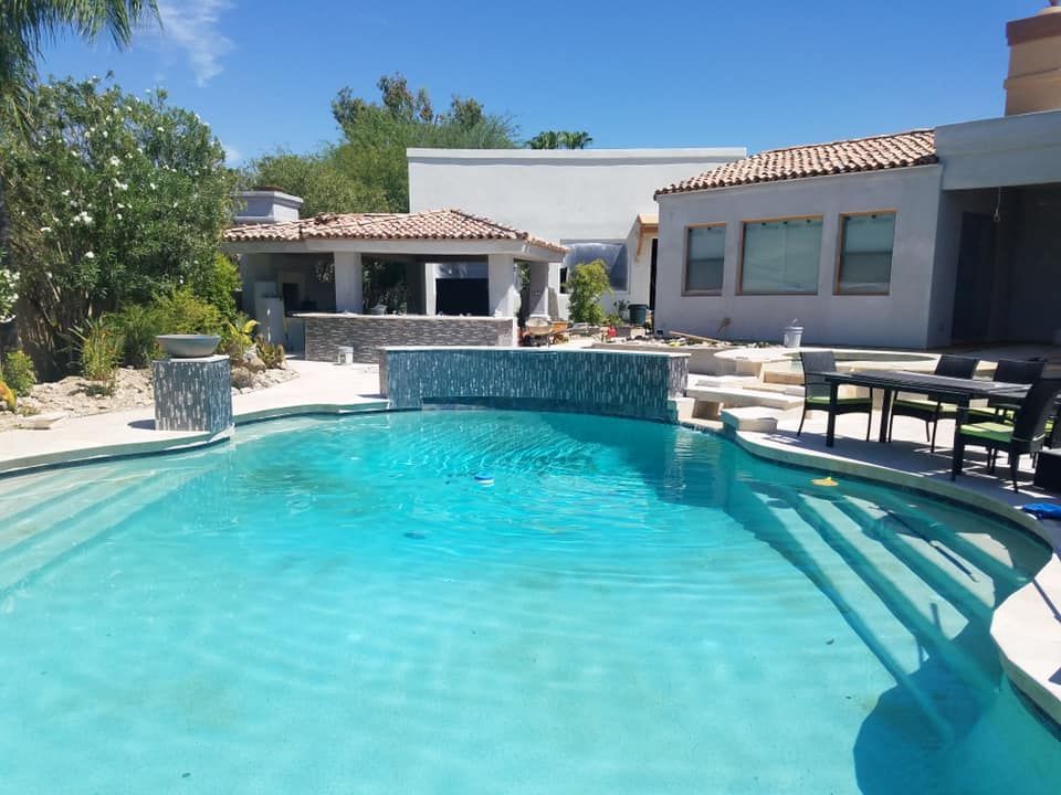 There is a large swimming pool in front of a house.
