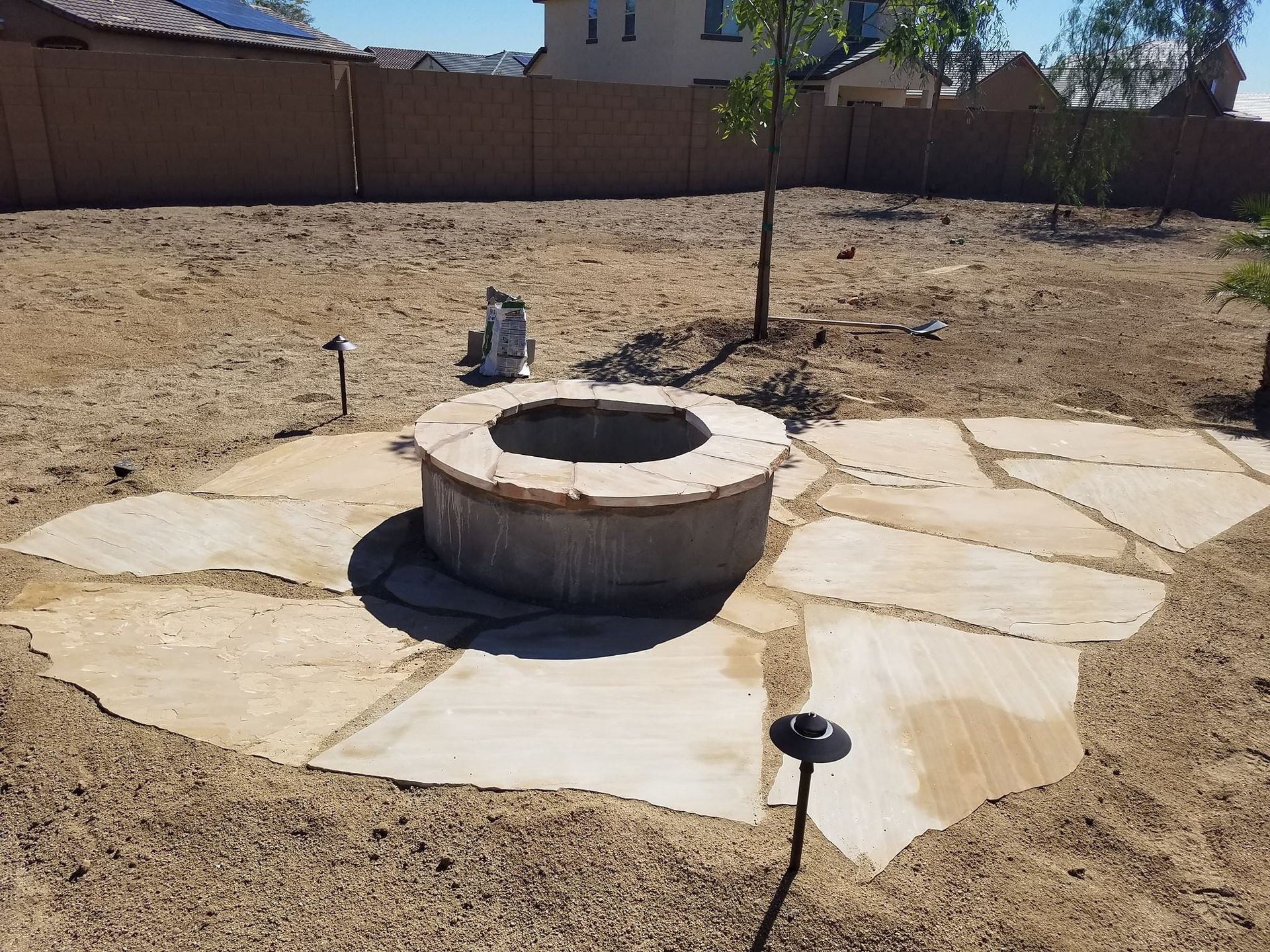 A fire pit is sitting in the middle of a dirt field.