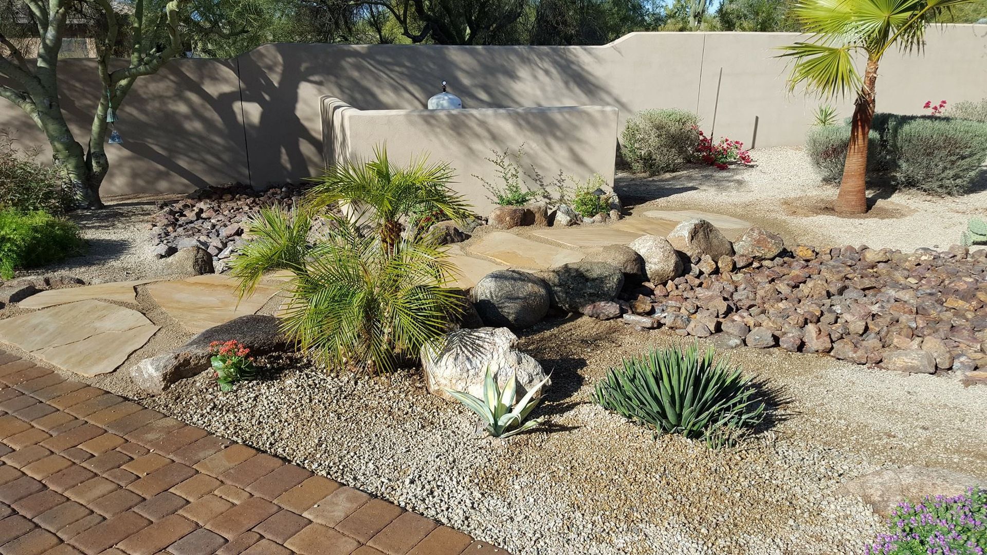 A brick walkway leading to a garden with rocks and plants