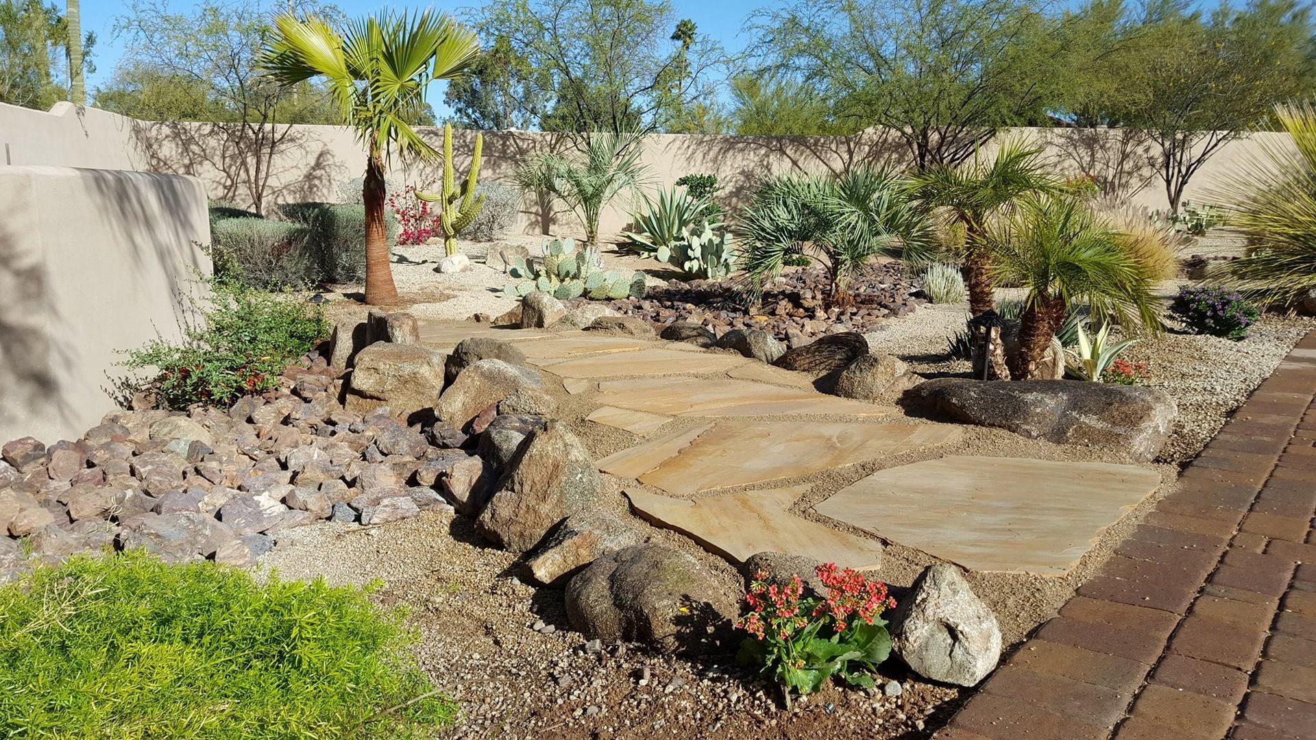 A lush green garden with a brick walkway surrounded by rocks and plants.
