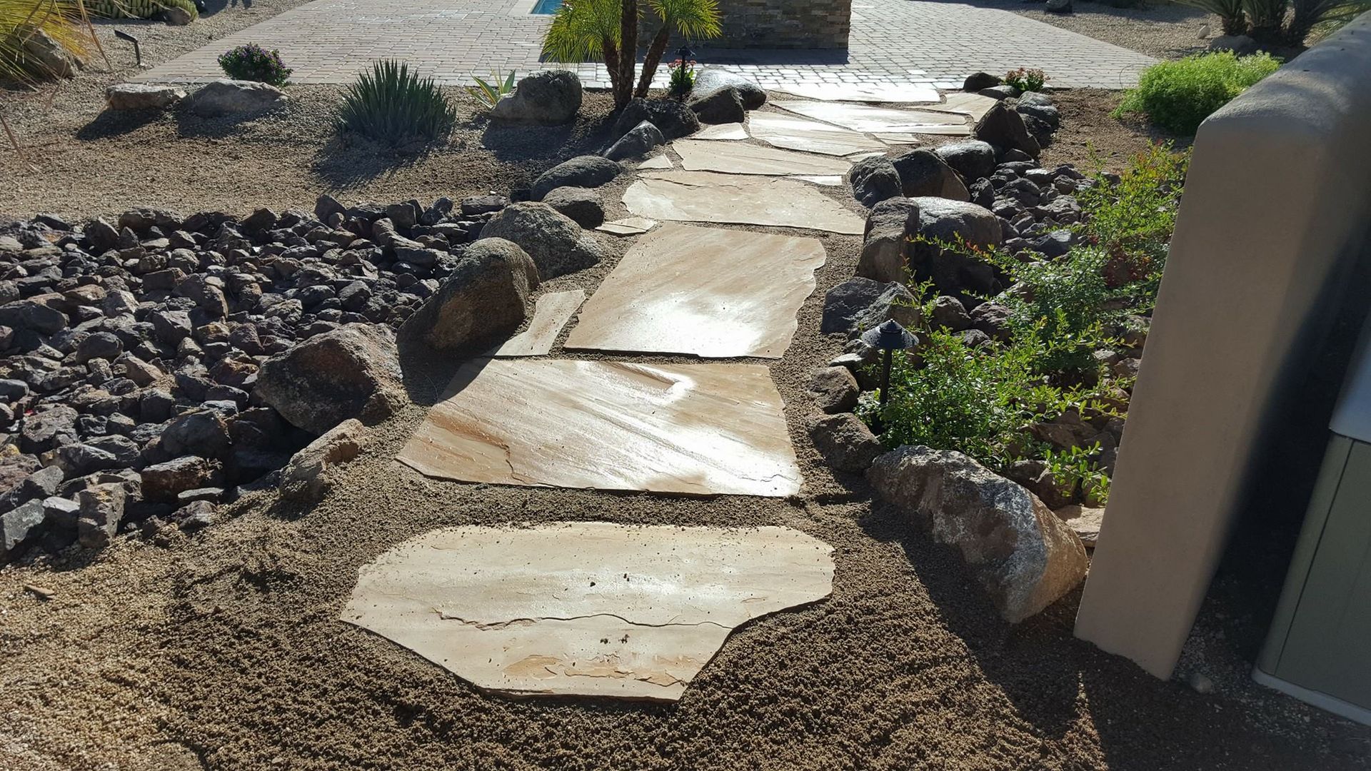 A stone walkway is surrounded by rocks and gravel.
