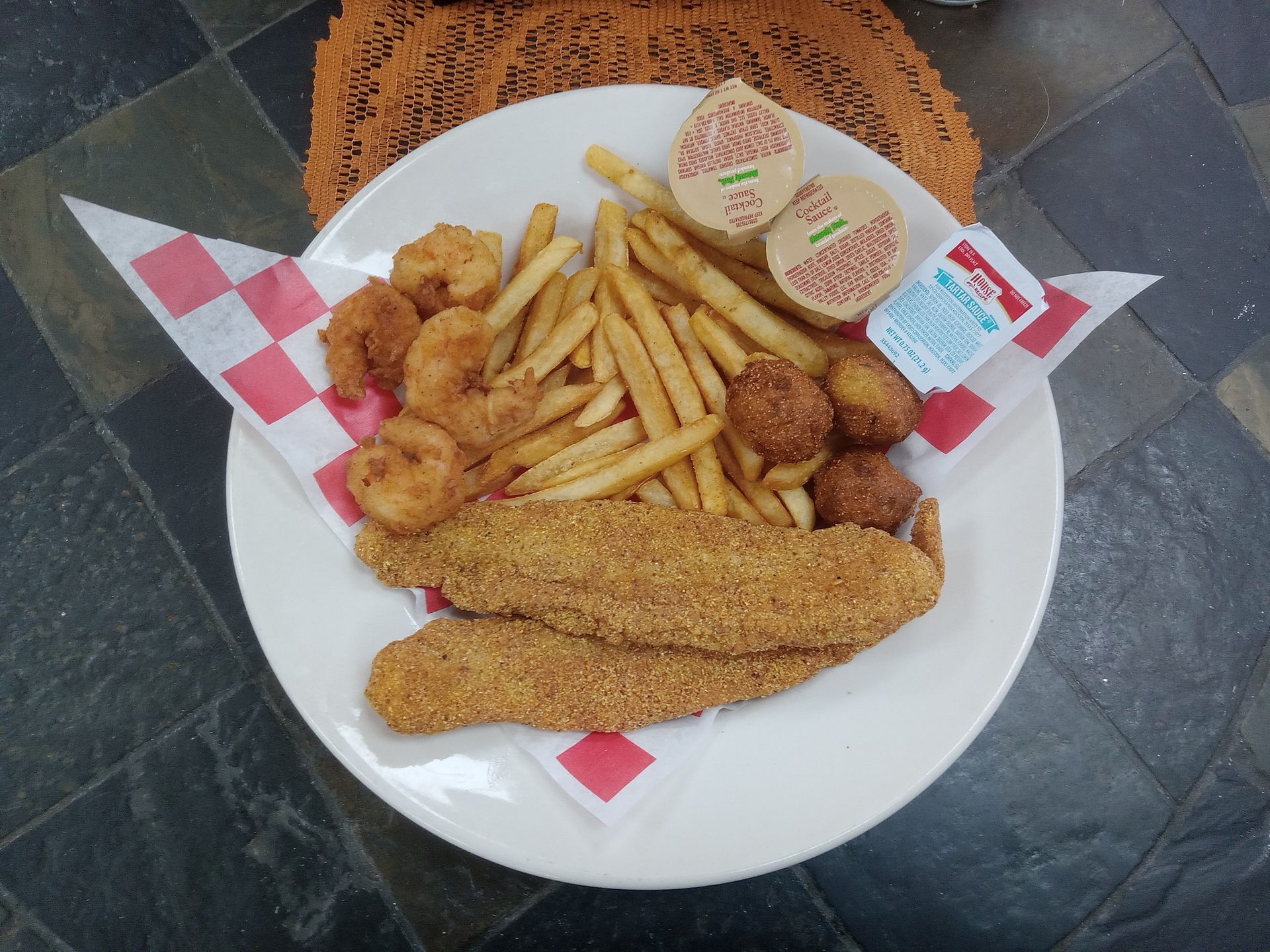 A white plate topped with fried fish , french fries and shrimp.