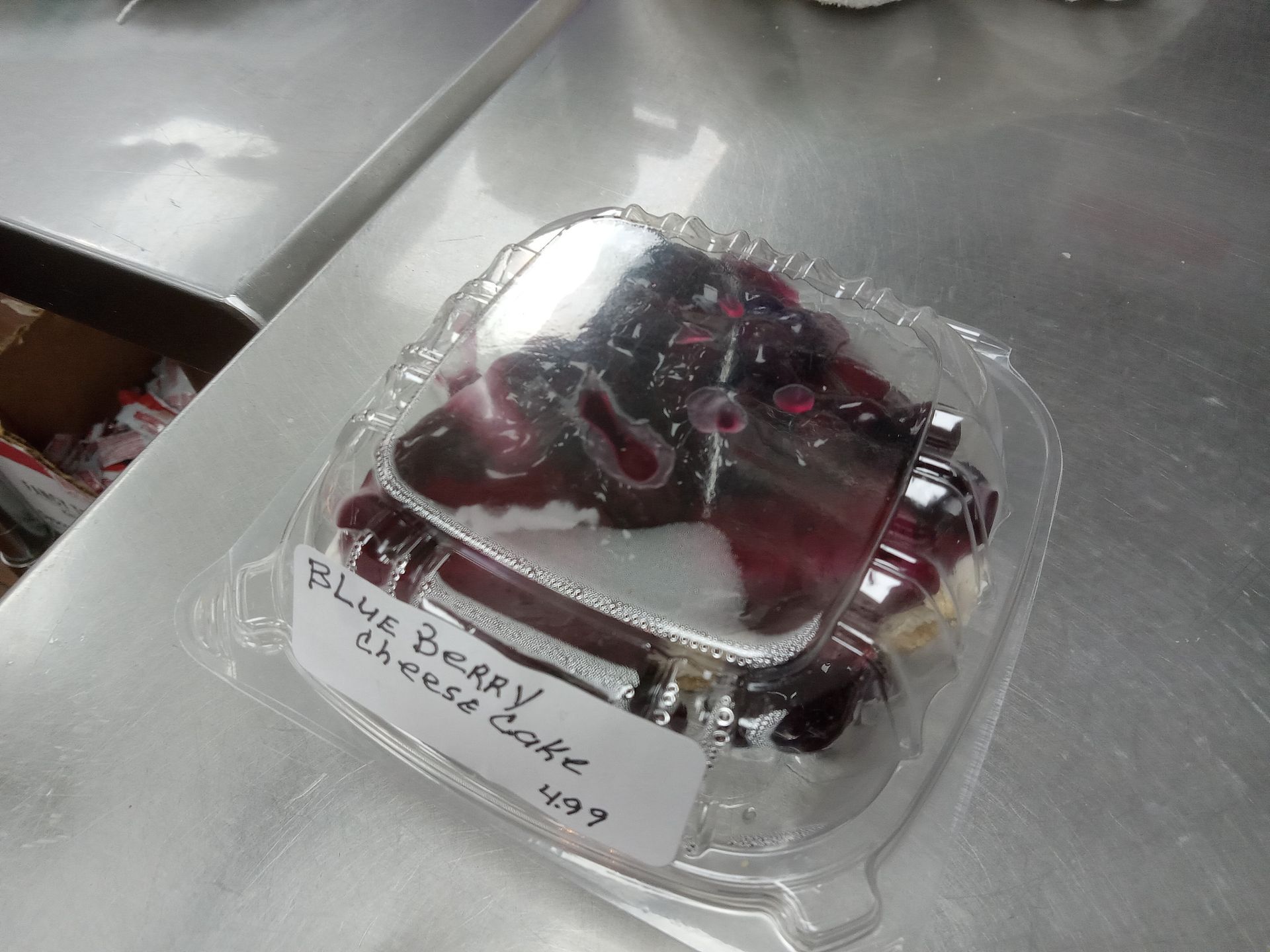 A piece of cake in a plastic container on a counter.