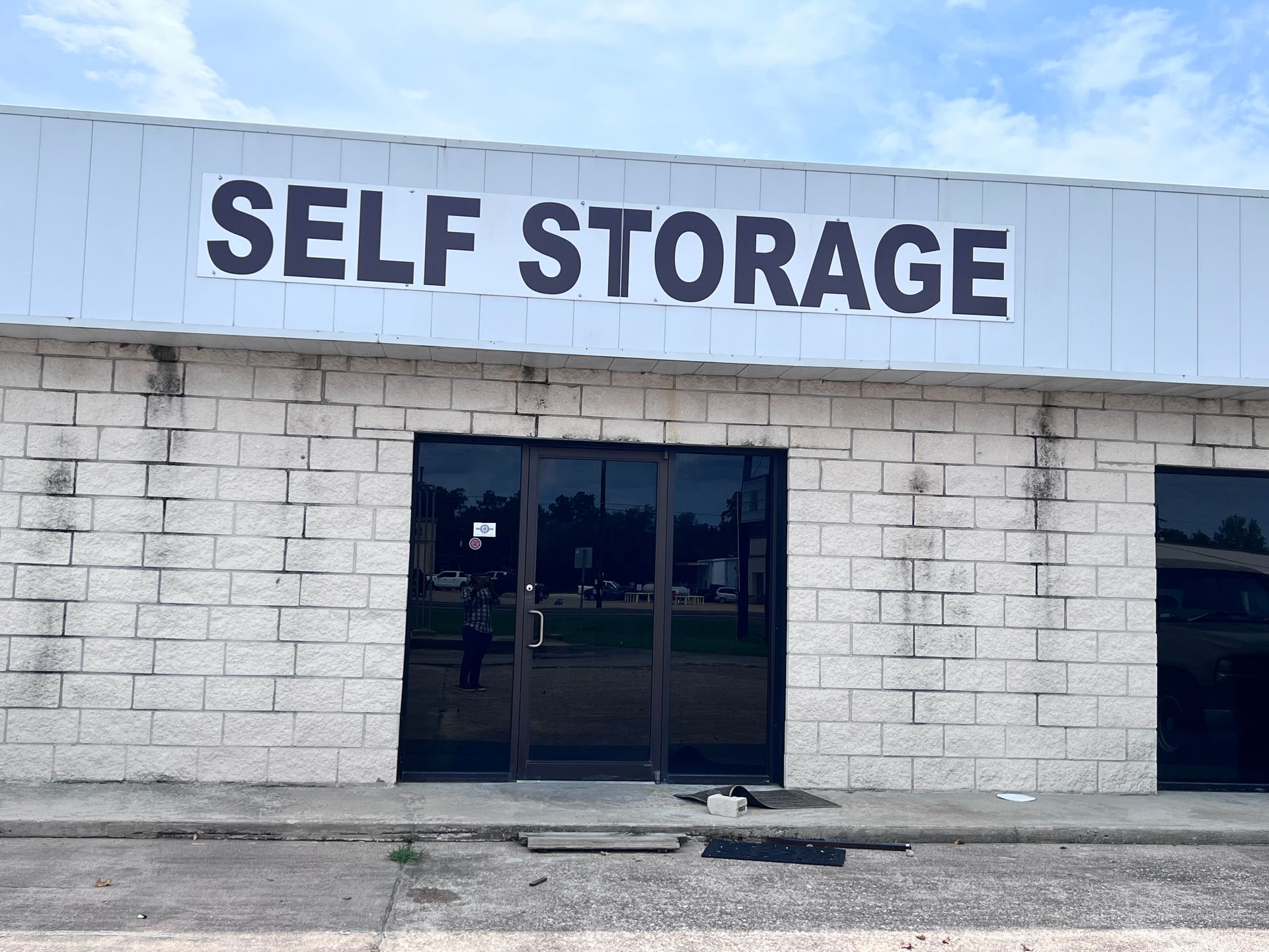 Exterior of a self-storage building with black windows, and white brick walls; the sign reads 