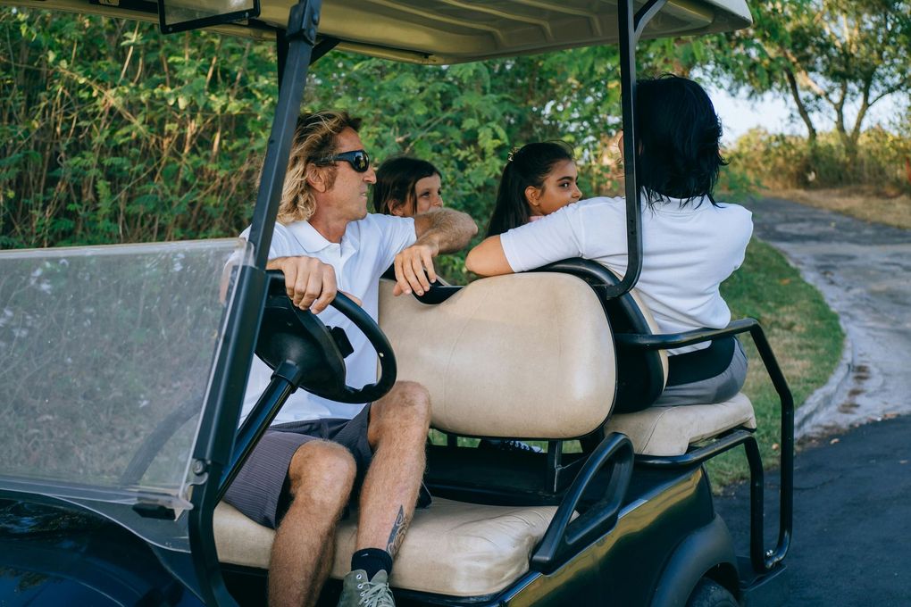 A group of people are sitting in a golf cart on a road.