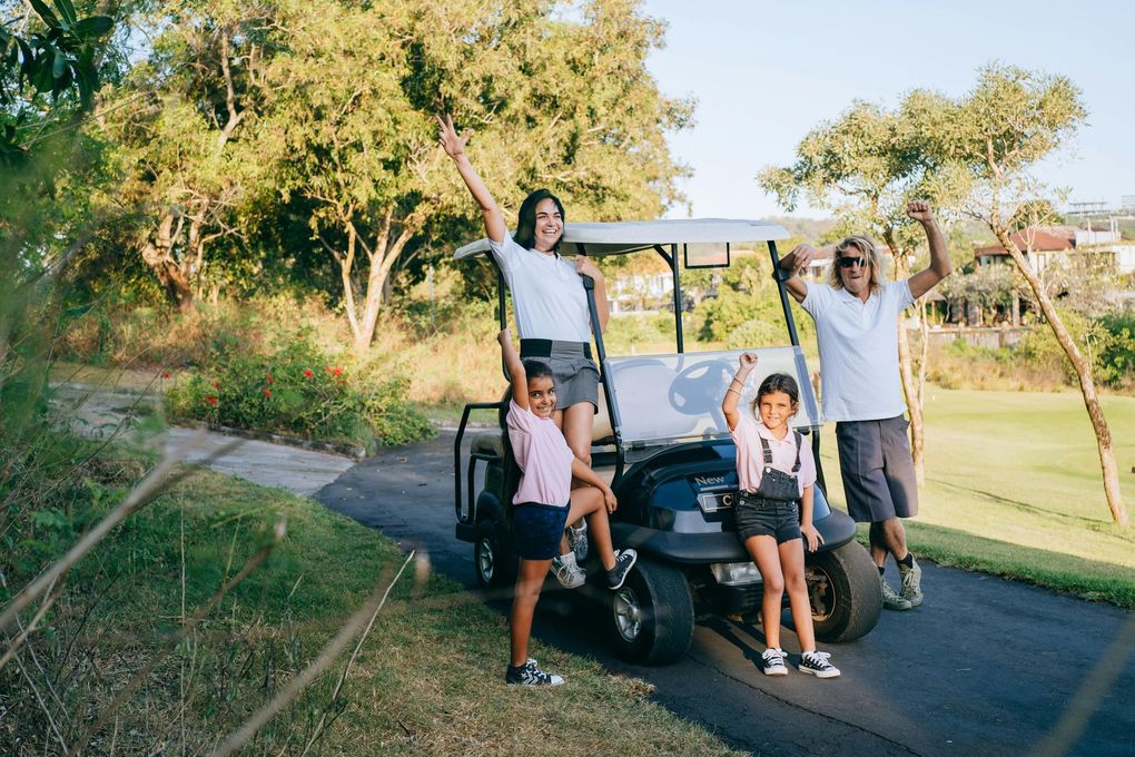 A family is standing next to a golf cart on a golf course.