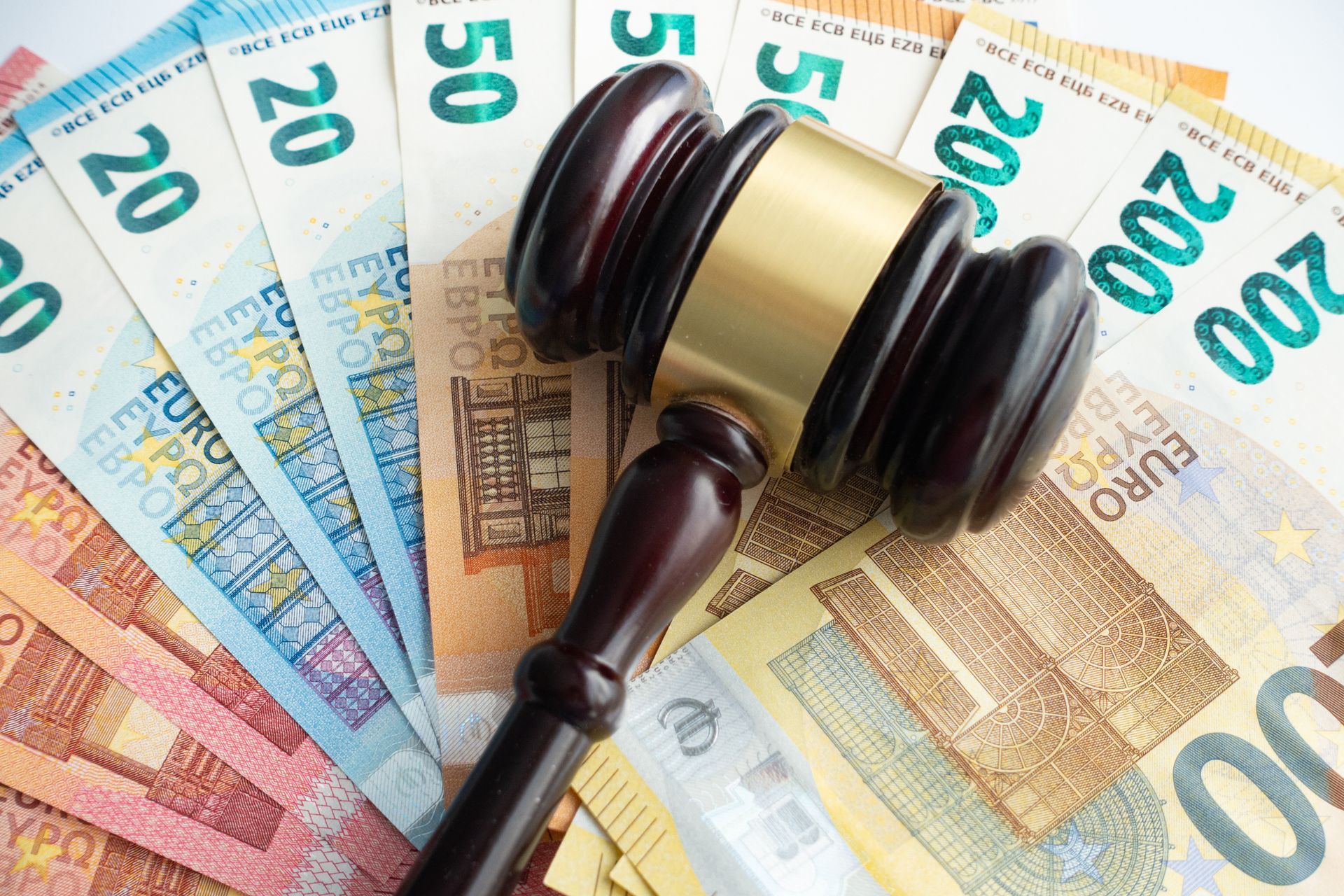 Un martelletto di legno poggiato su una disposizione a ventaglio di varie banconote in euro.