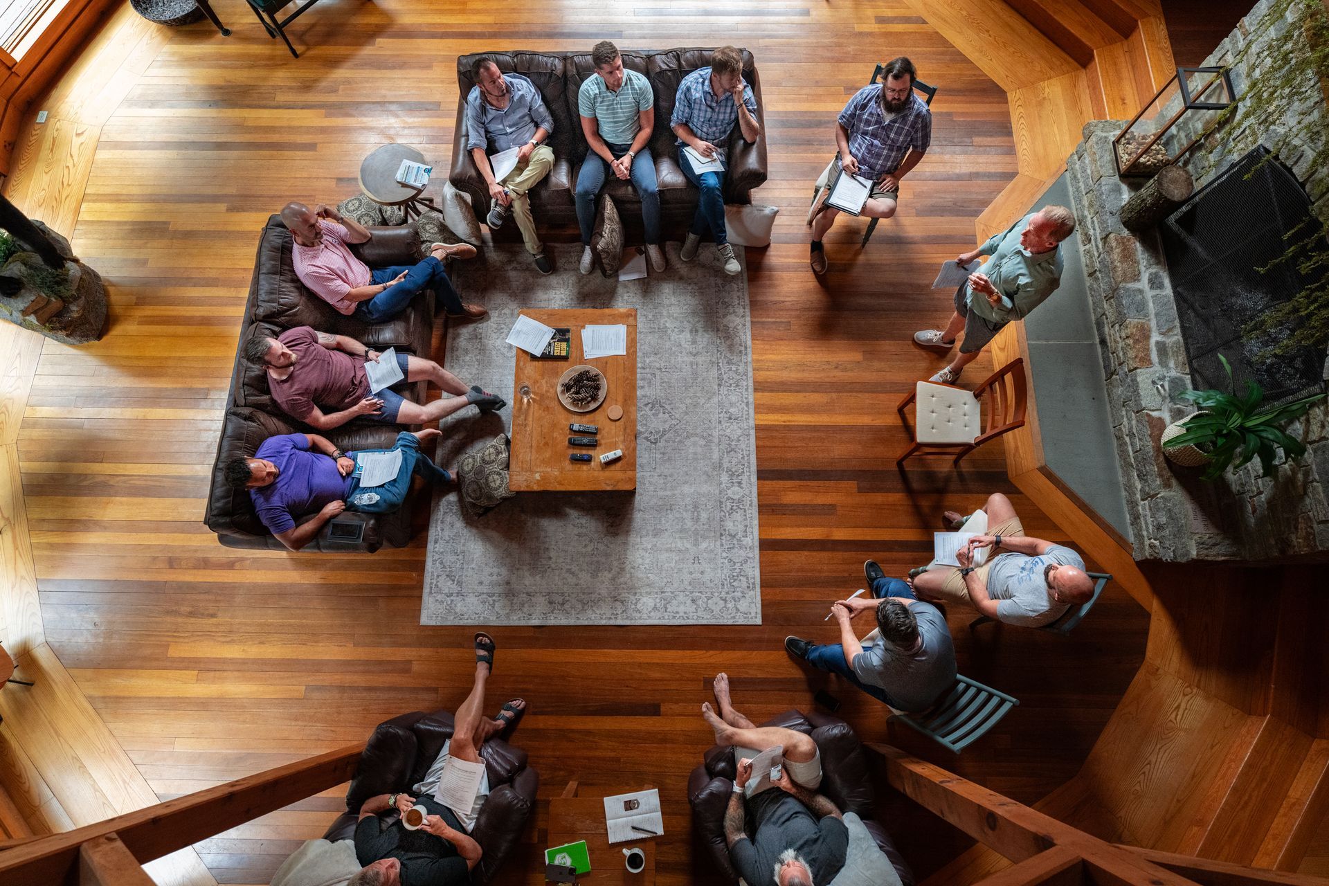 A group of dads are sitting around a table in a living room.