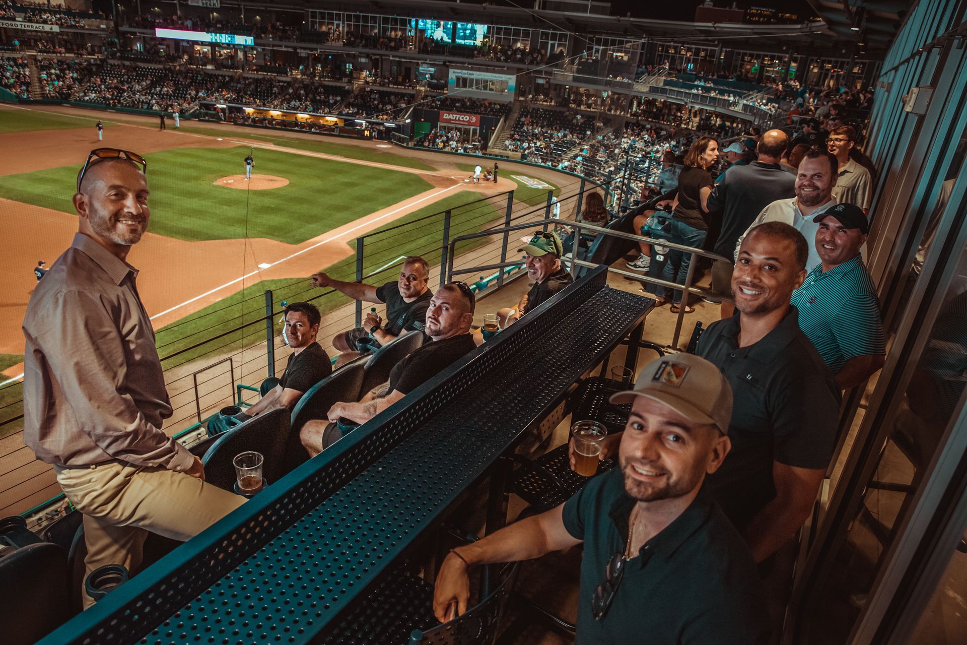 A group of men are sitting in a stadium watching a baseball game.