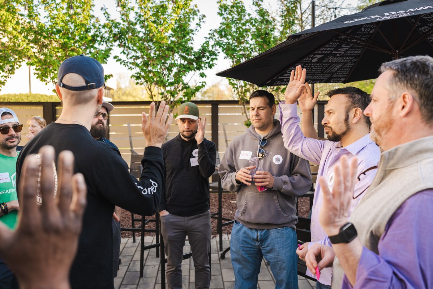 A group of dads are standing in a circle with their hands in the air.