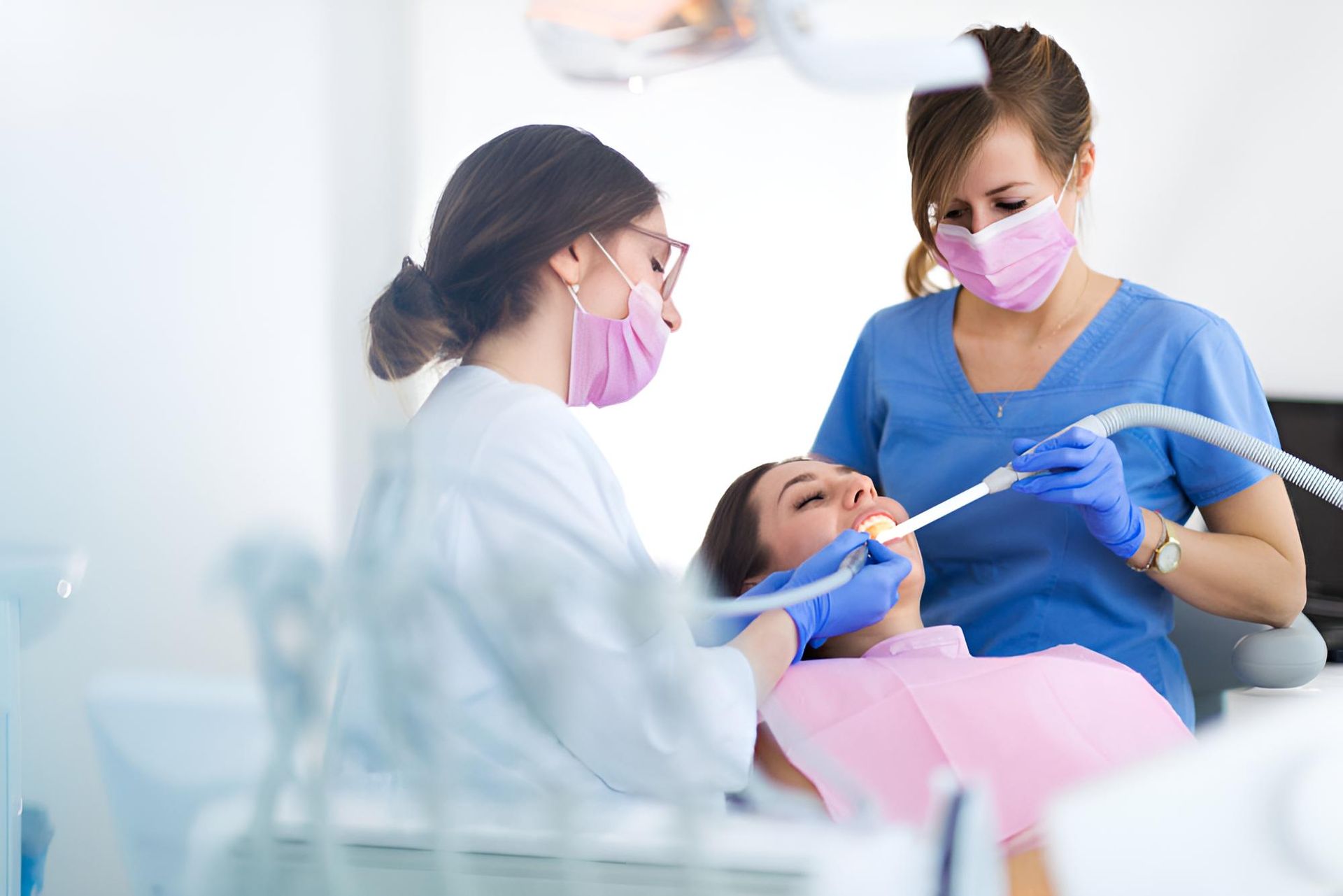 A Woman is Getting Her Teeth Examined by Two Female Dentists — Trower Dental In Casuarina, NT