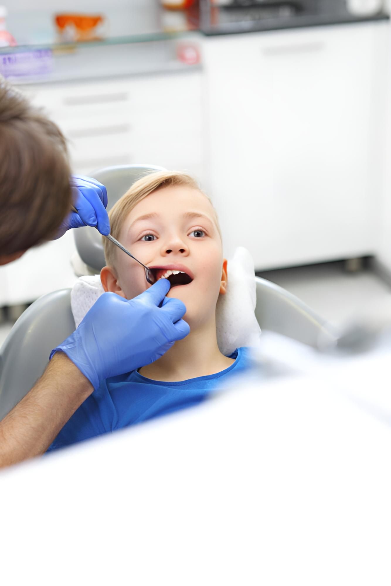 A Young Boy is Sitting in a Dental Chair Getting His Teeth Examined by a Dentist — Trower Dental In Darwin, NT