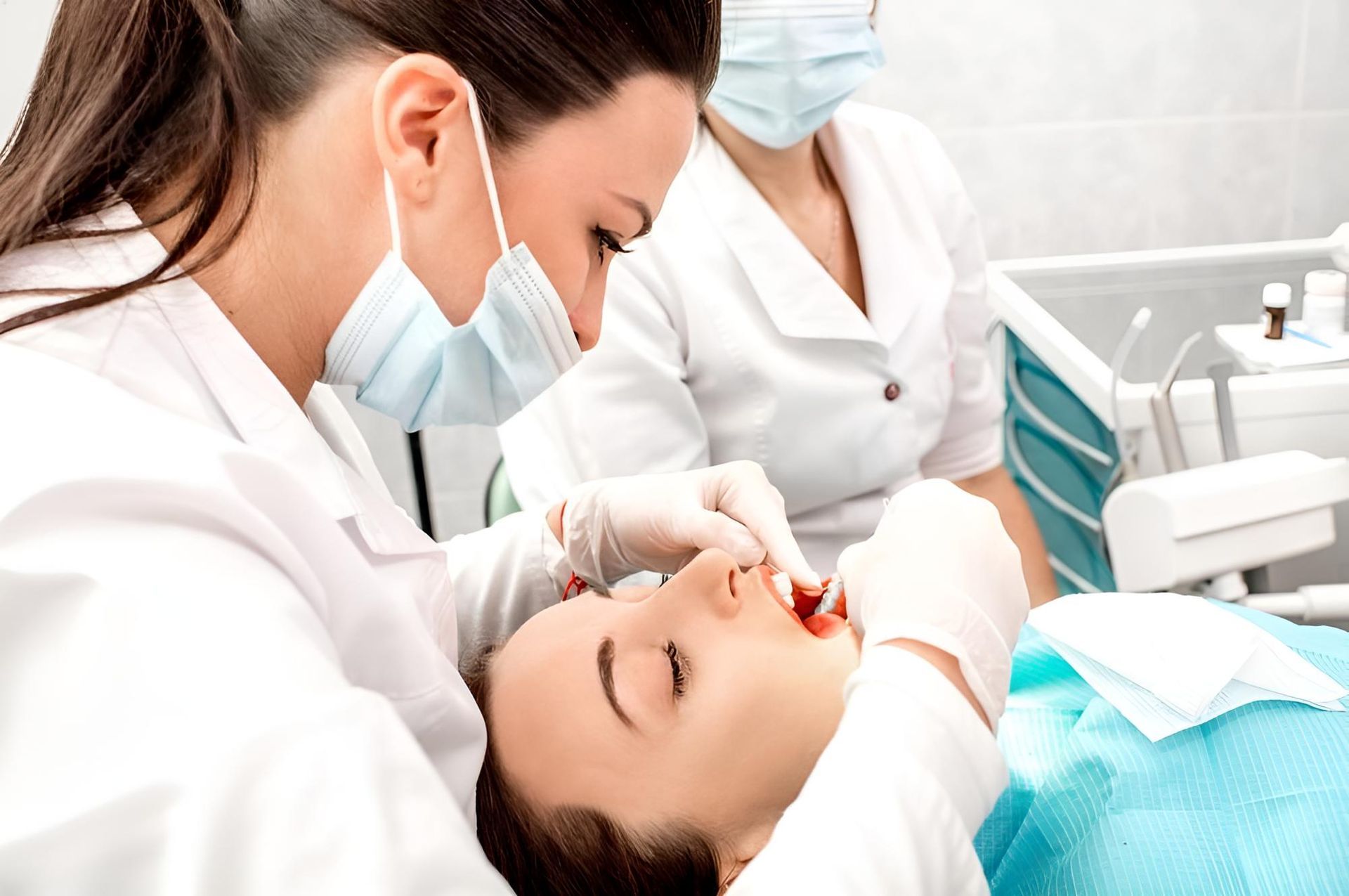A Woman is Getting Her Teeth Examined by Two Female Dentists — Trower Dental In Casuarina, NT