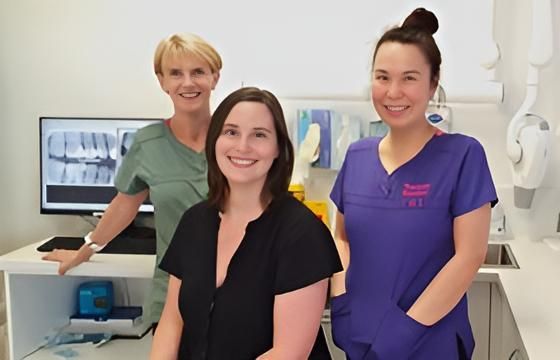 Three Women Are Posing for a Picture in a Dental Office — Trower Dental In Casuarina, NT