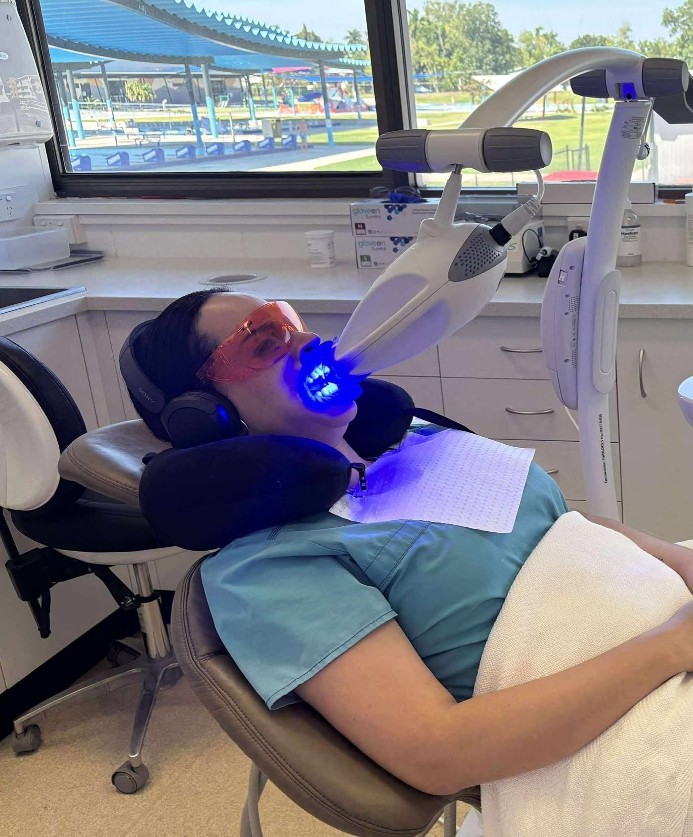 Person in dental chair undergoing teeth whitening treatment with blue light. — Trower Dental In Casuarina, NT