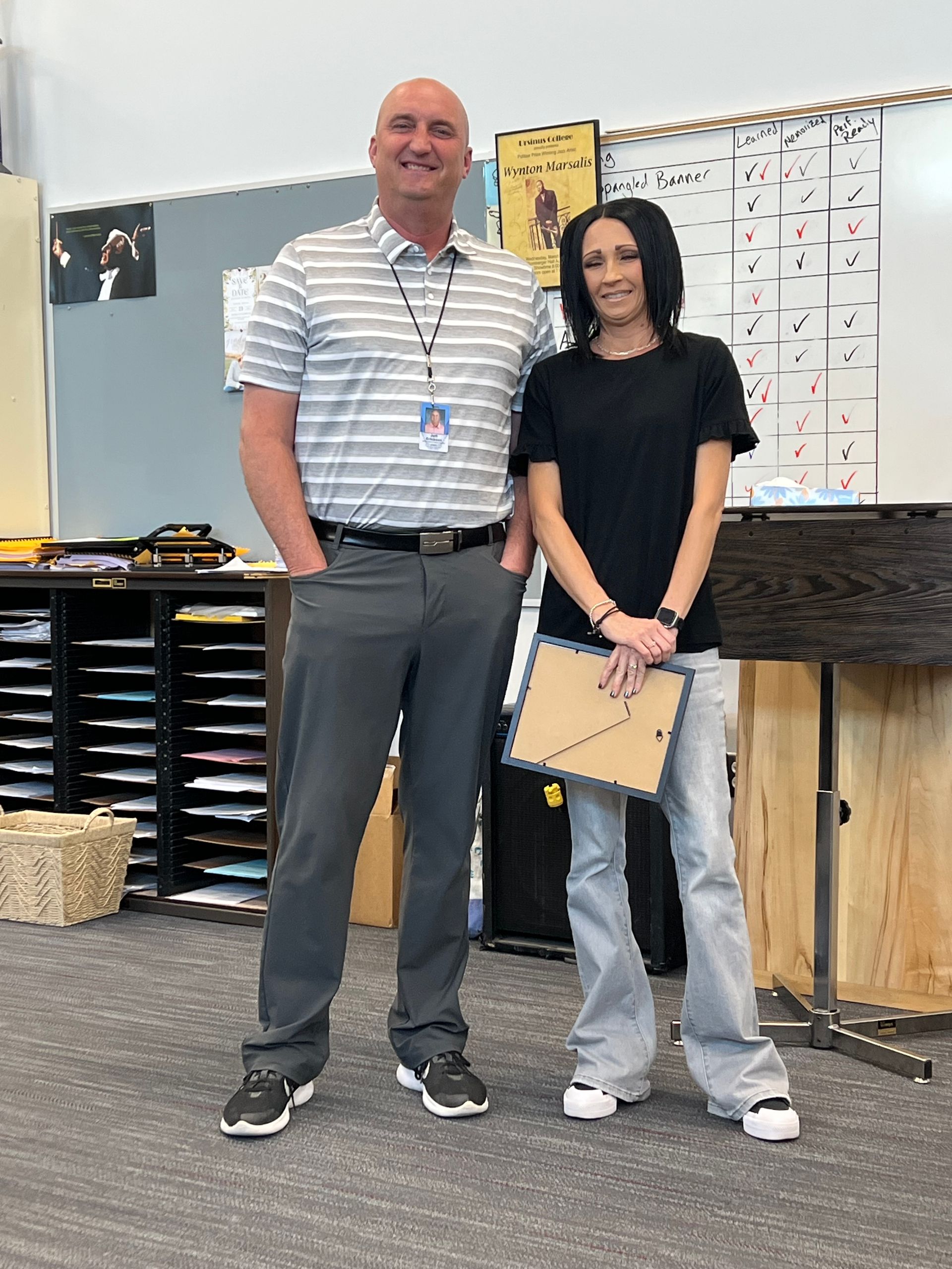A man and a woman are standing next to each other in a classroom.