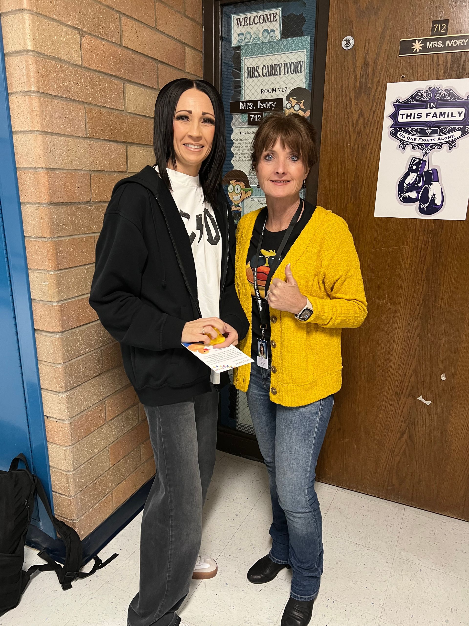 Two women are standing next to each other in front of a door.