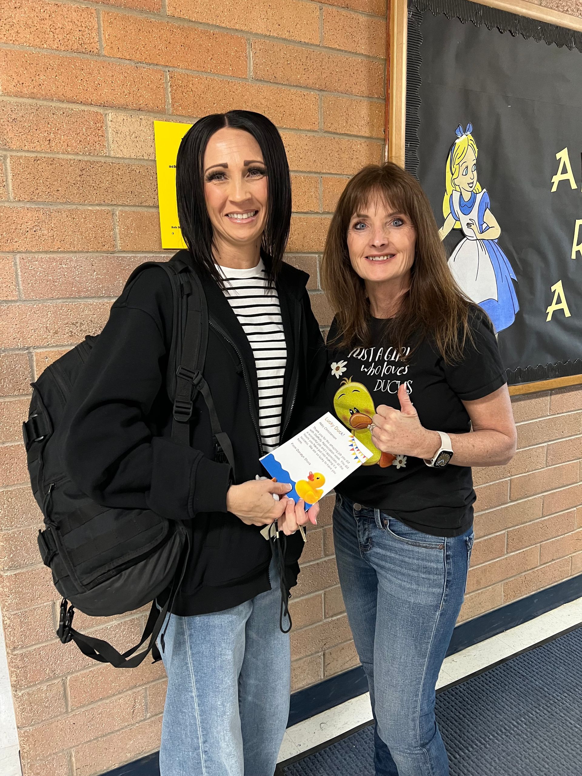 Two women are standing next to each other in a hallway.