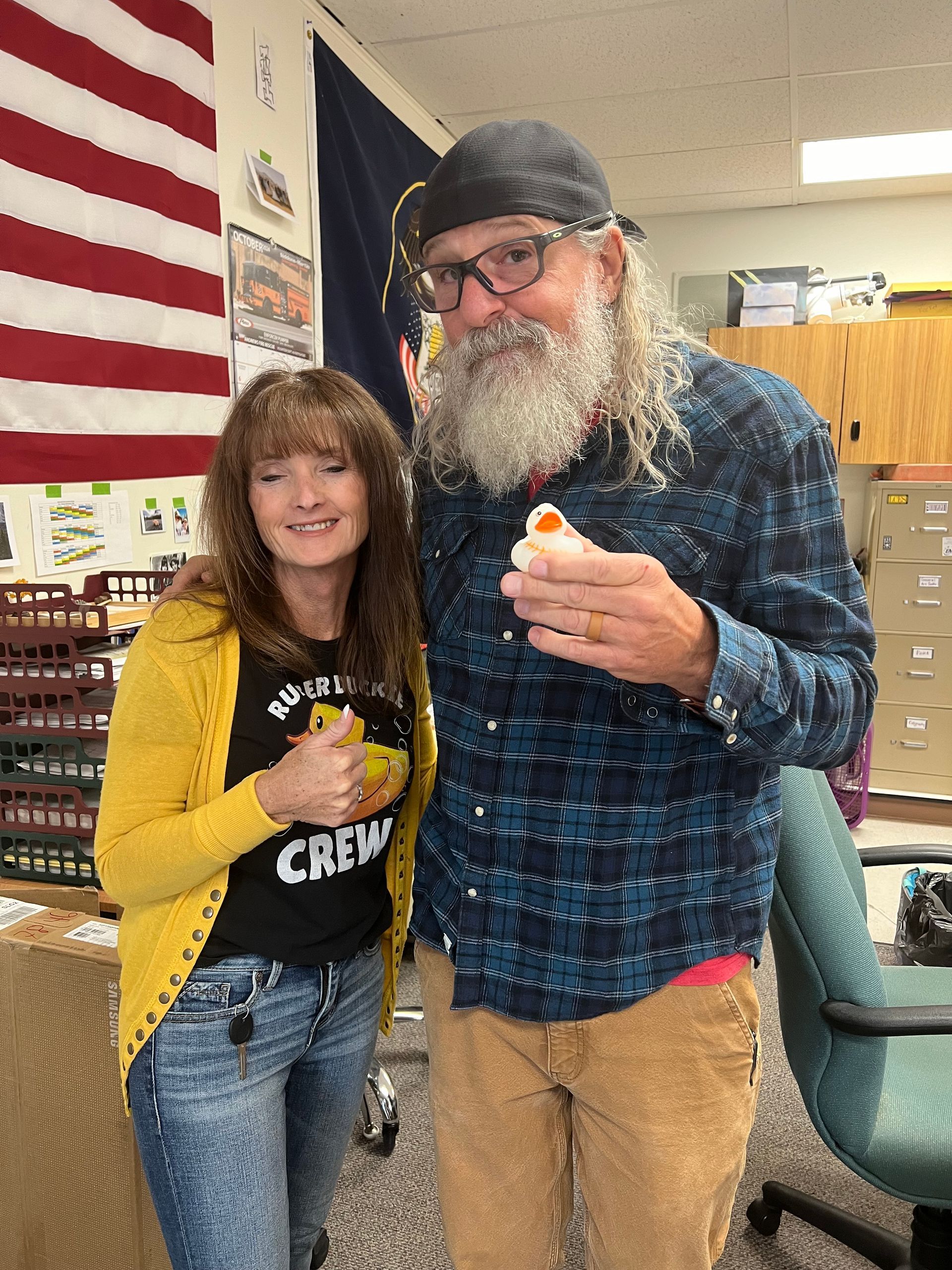 A man and a woman are posing for a picture in front of an american flag.