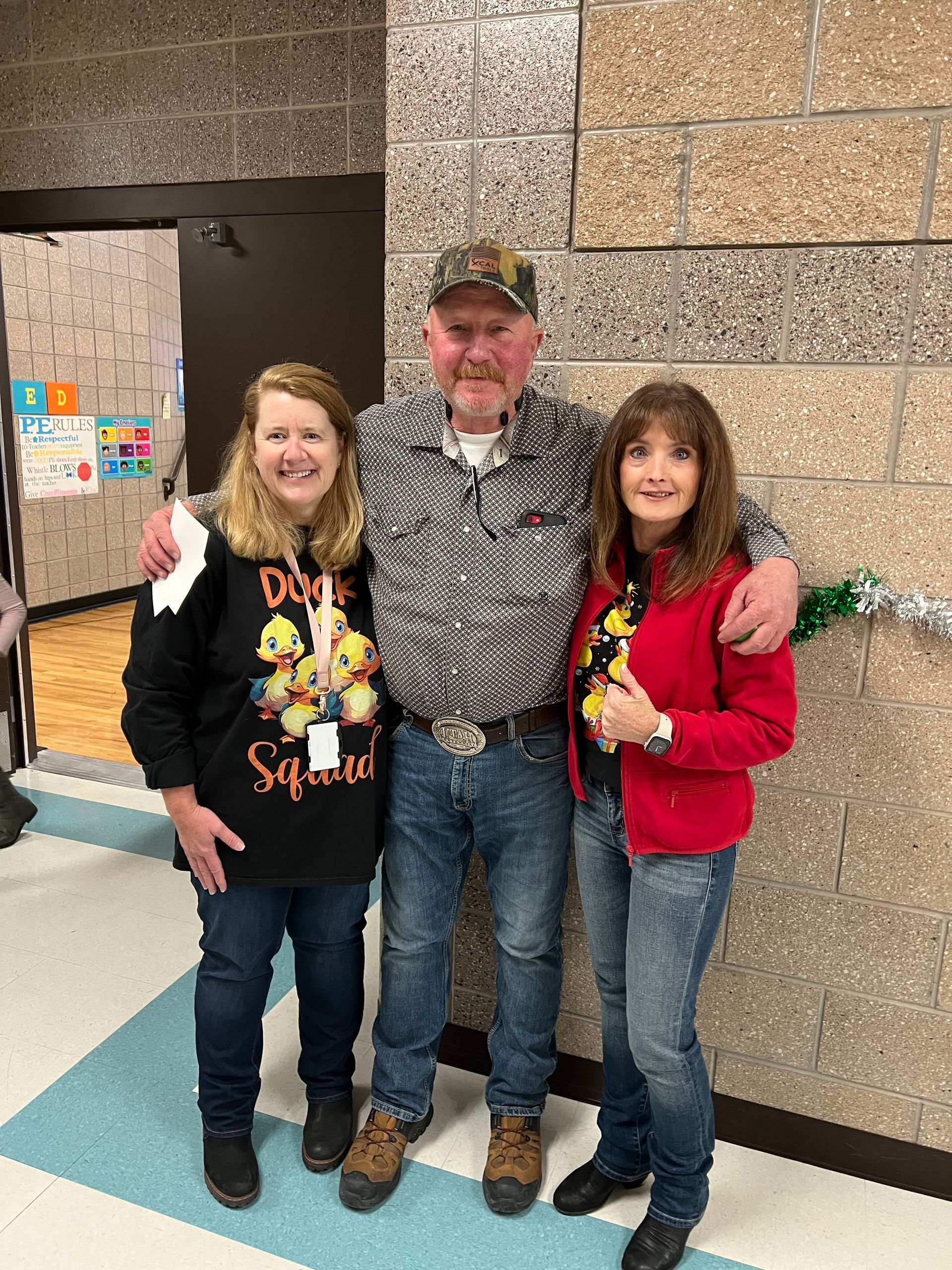 A man and two women are posing for a picture in a hallway.