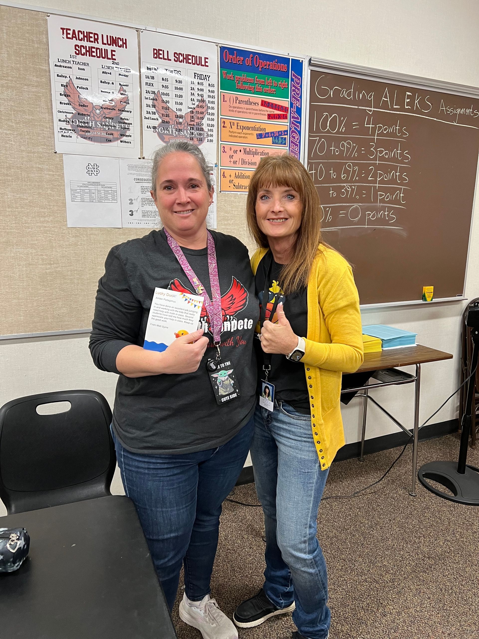 Two women are posing for a picture in a classroom.