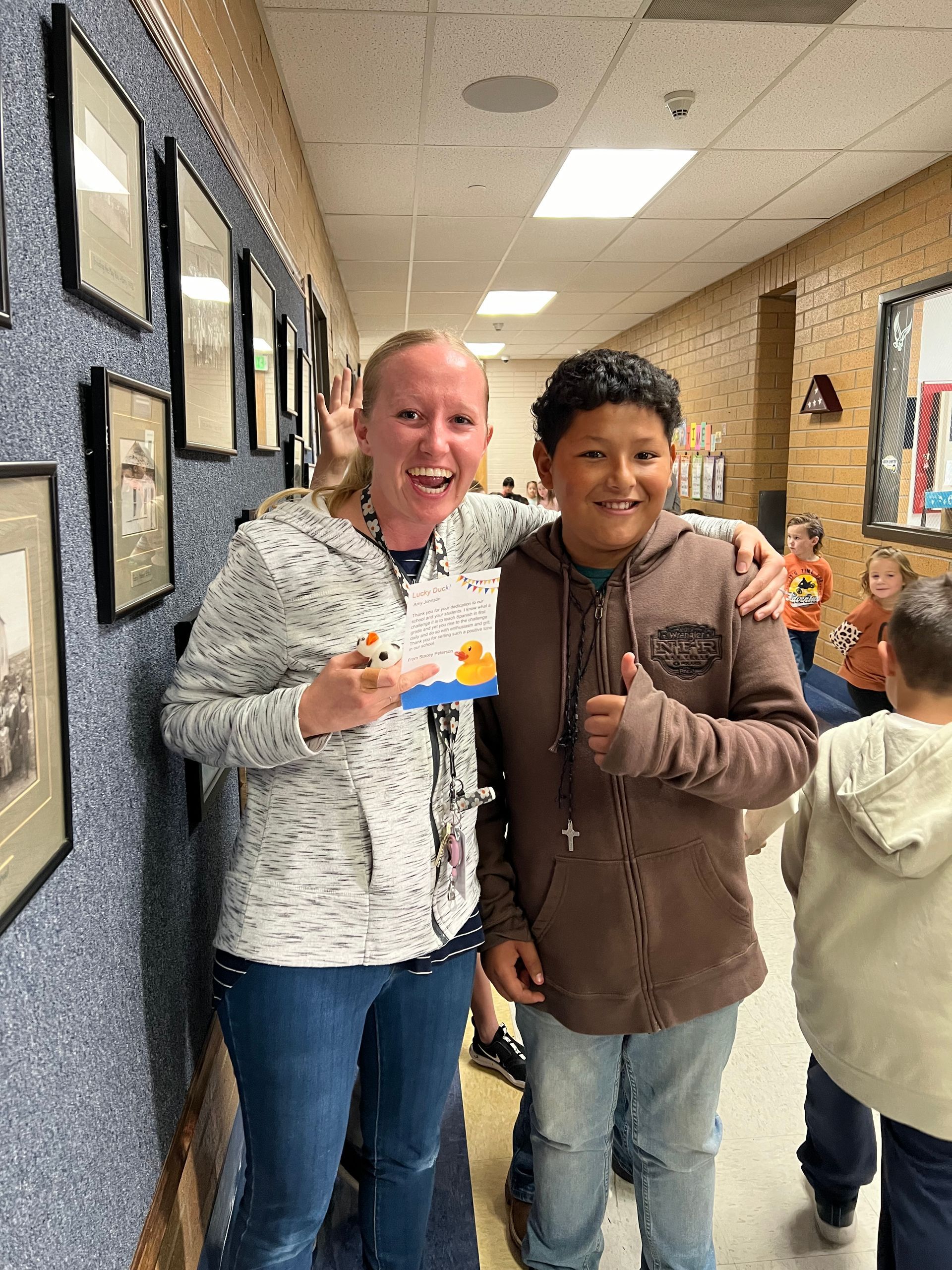 A woman and a boy are standing next to each other in a hallway.