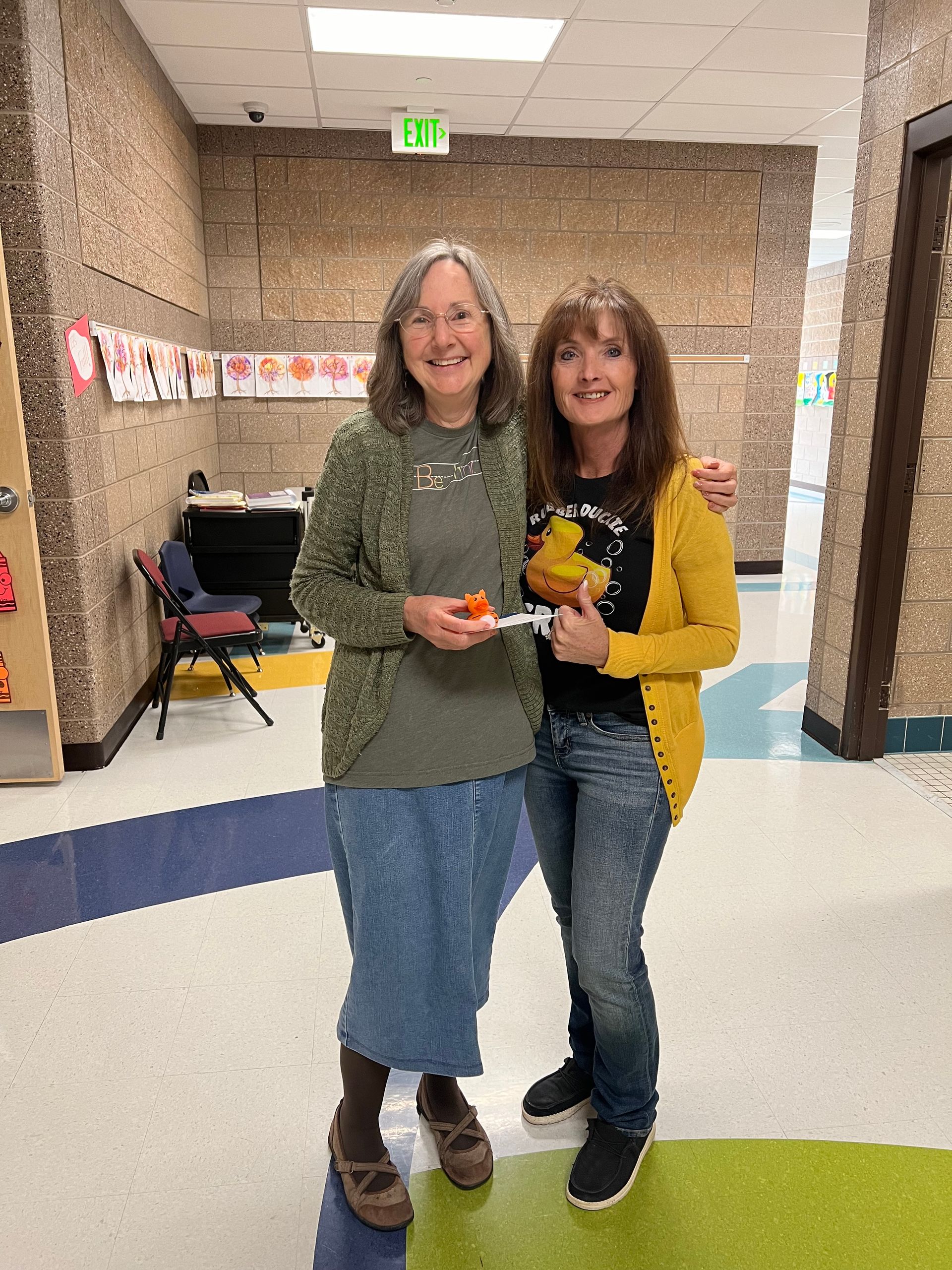 Two women are standing next to each other in a hallway.