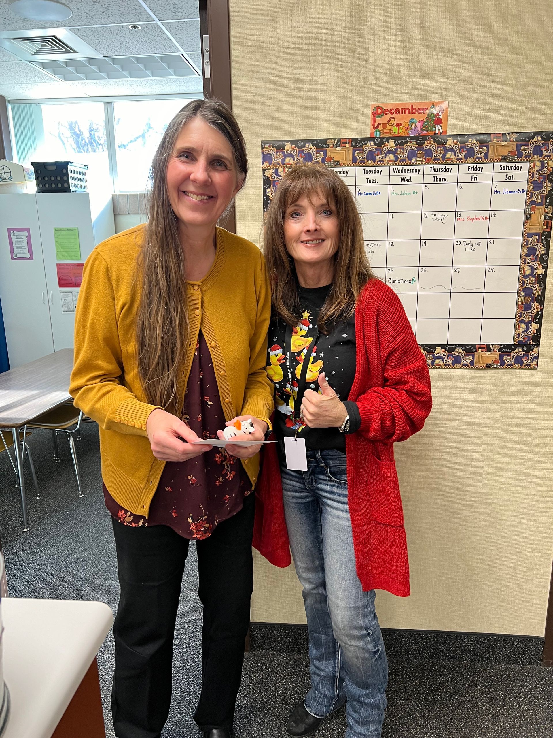 Two women are standing next to each other in a classroom.