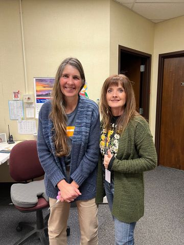 Two women are standing next to each other in a room.