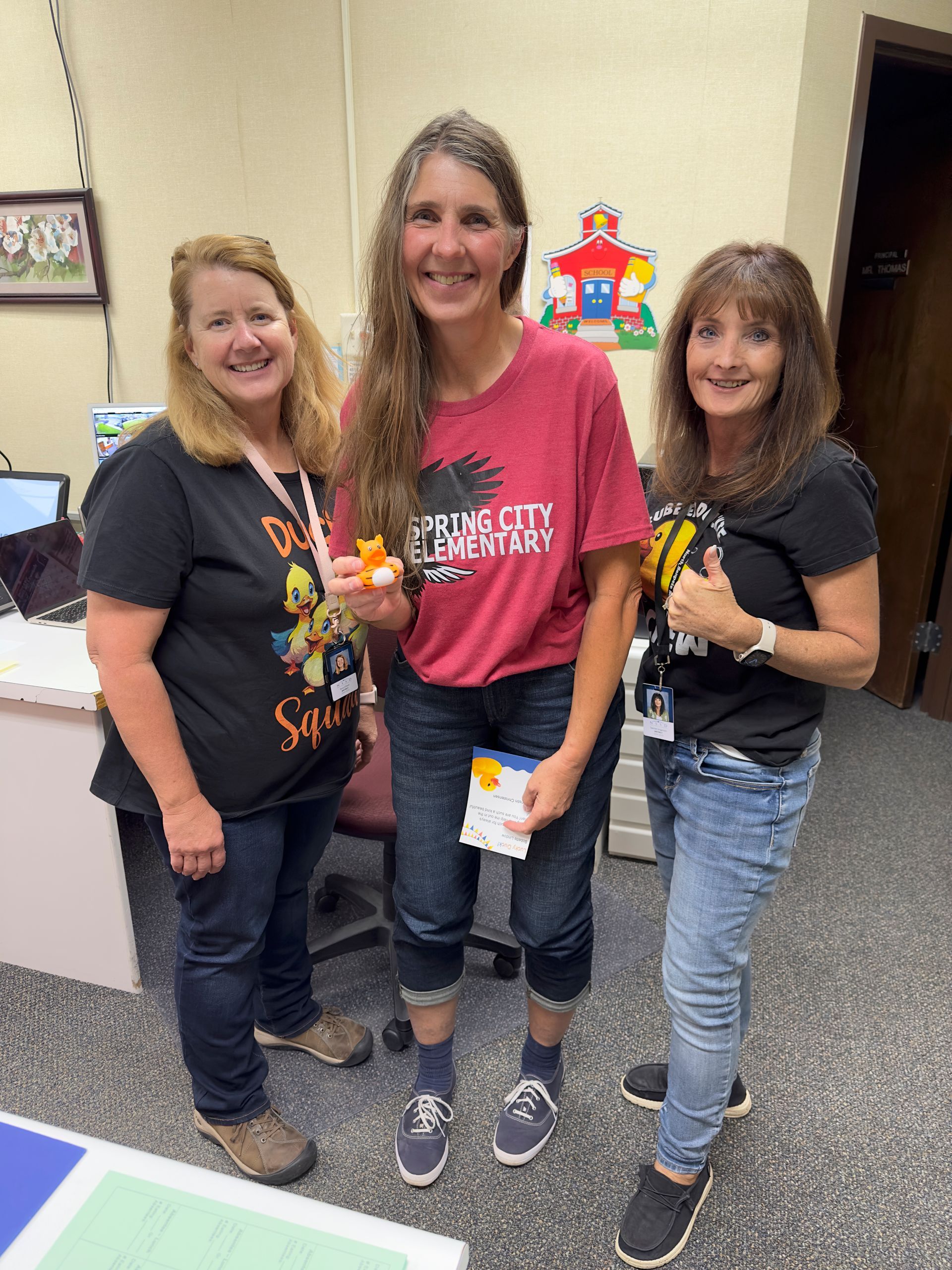 Three women are standing next to each other in a room and smiling.