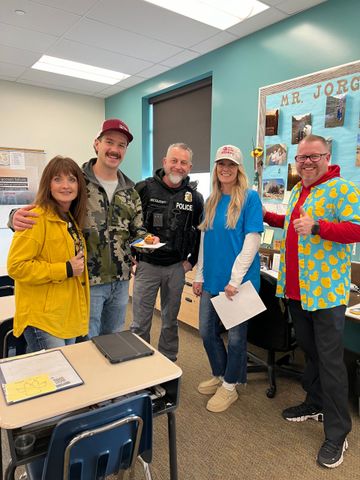 A group of people are posing for a picture in a classroom.