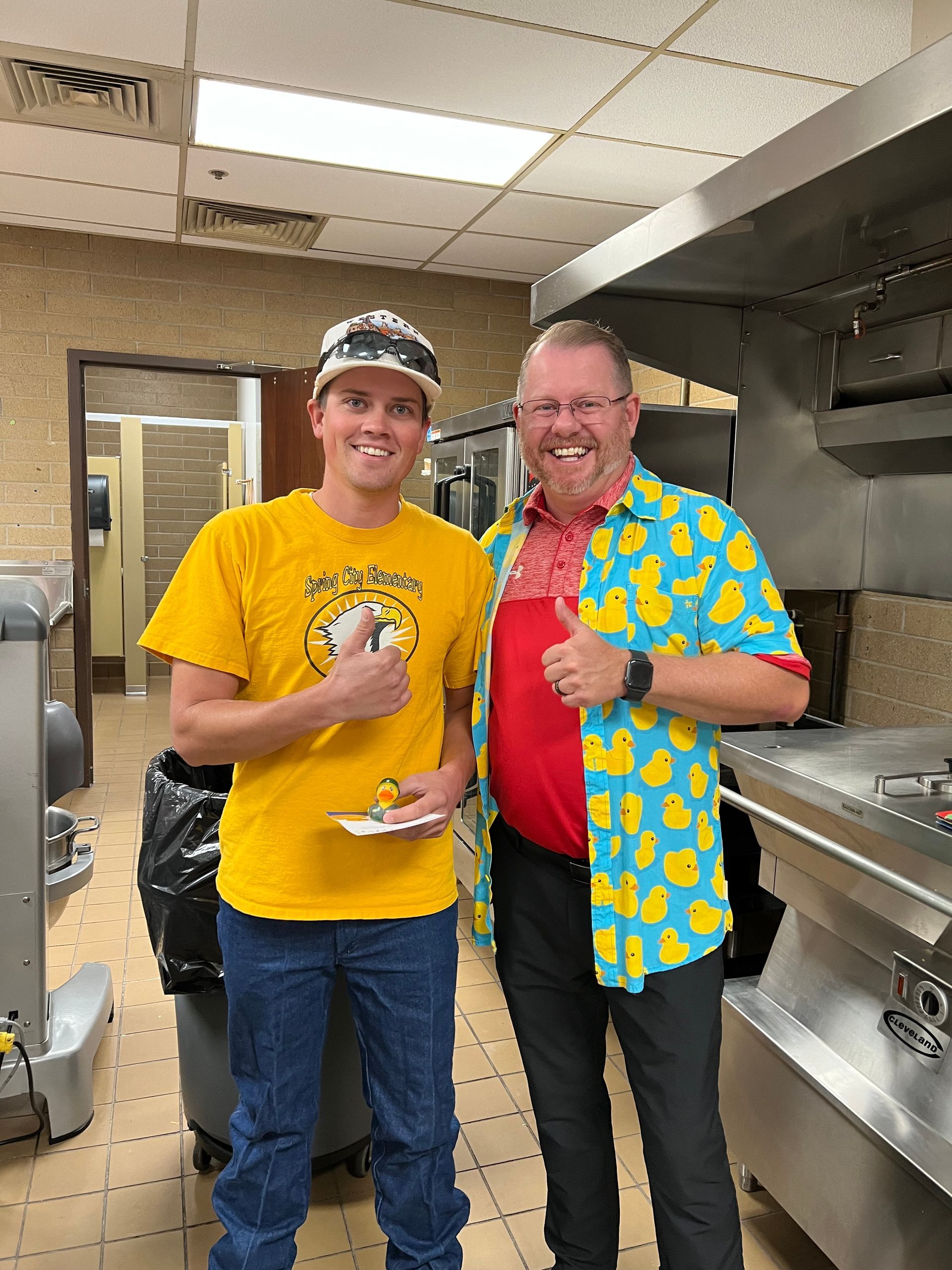 Two men are standing next to each other in a kitchen.