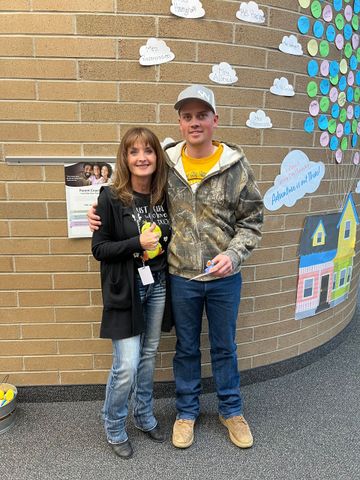 A man and a woman are standing next to each other in front of a brick wall.