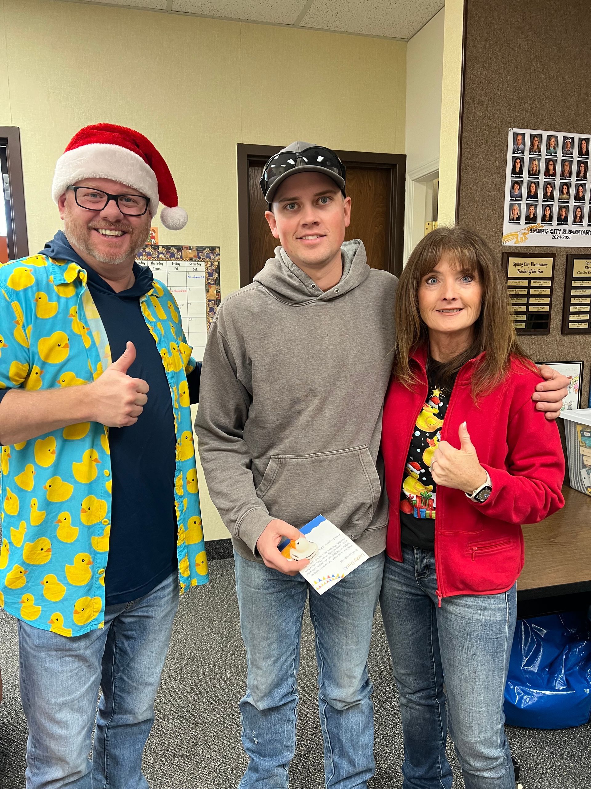 A man wearing a santa hat is standing next to a woman and giving a thumbs up.