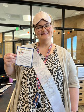 Woman wearing a sleep mask and sash that reads 