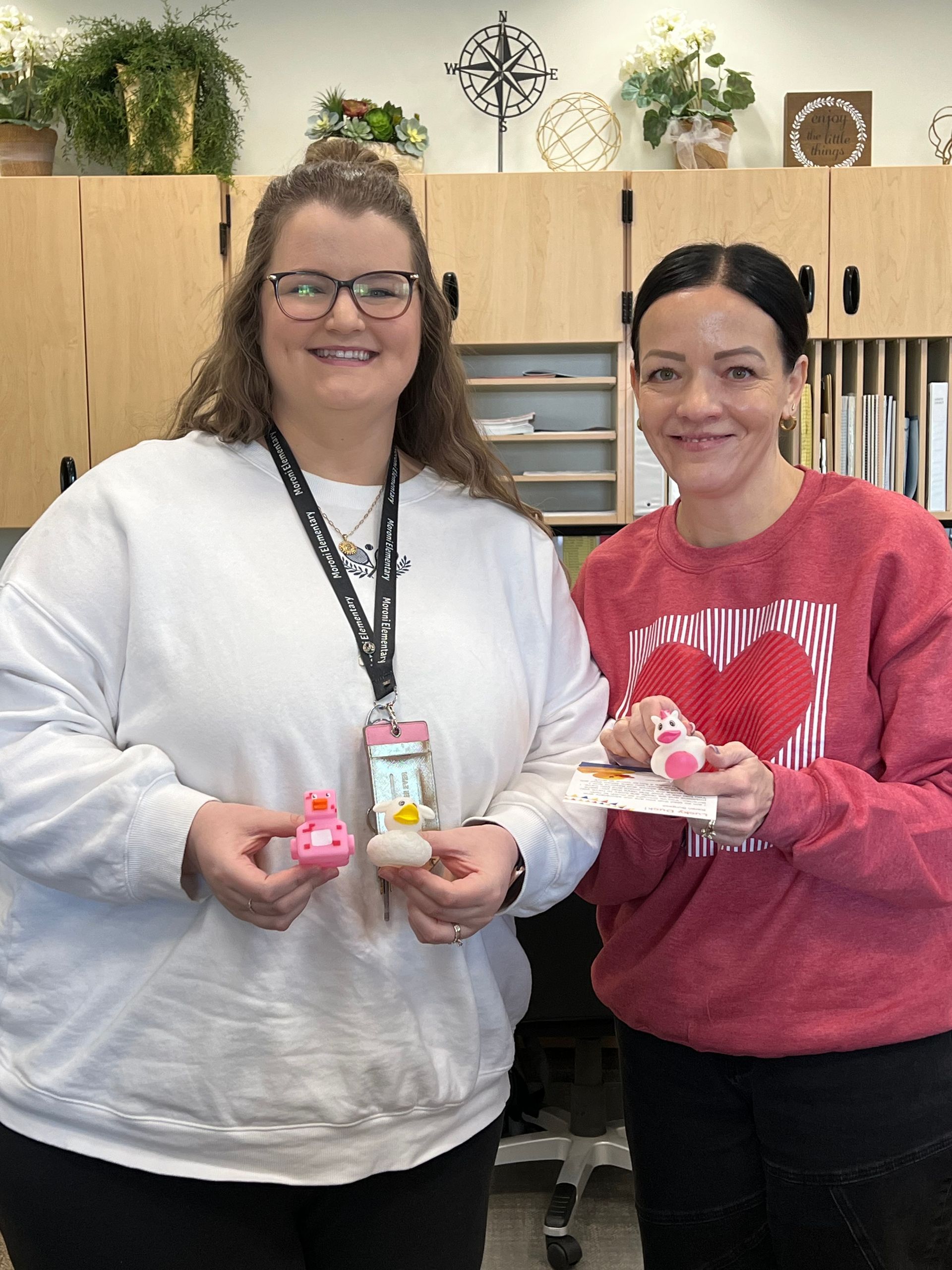 Two women are standing next to each other holding cupcakes.