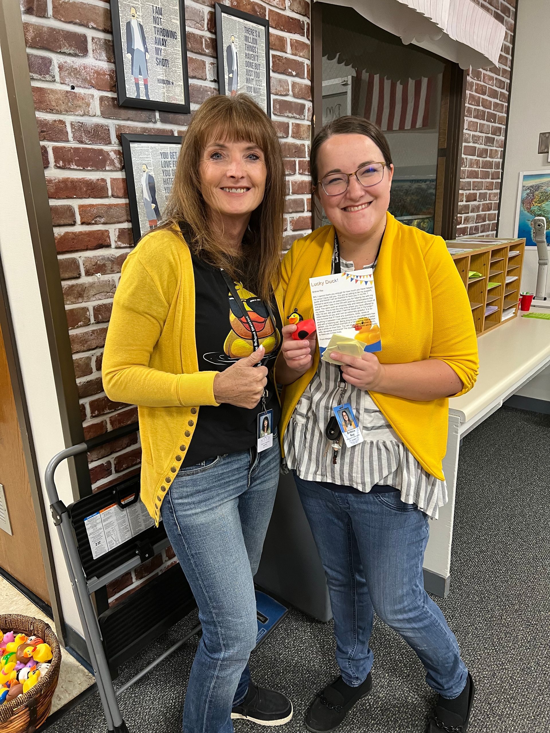 Two women in yellow sweaters are standing next to each other in a room.