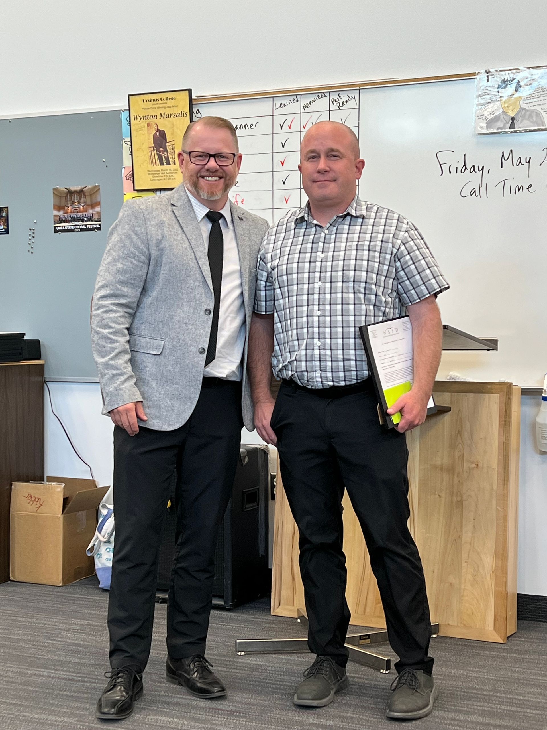 Two men are standing next to each other in a classroom.