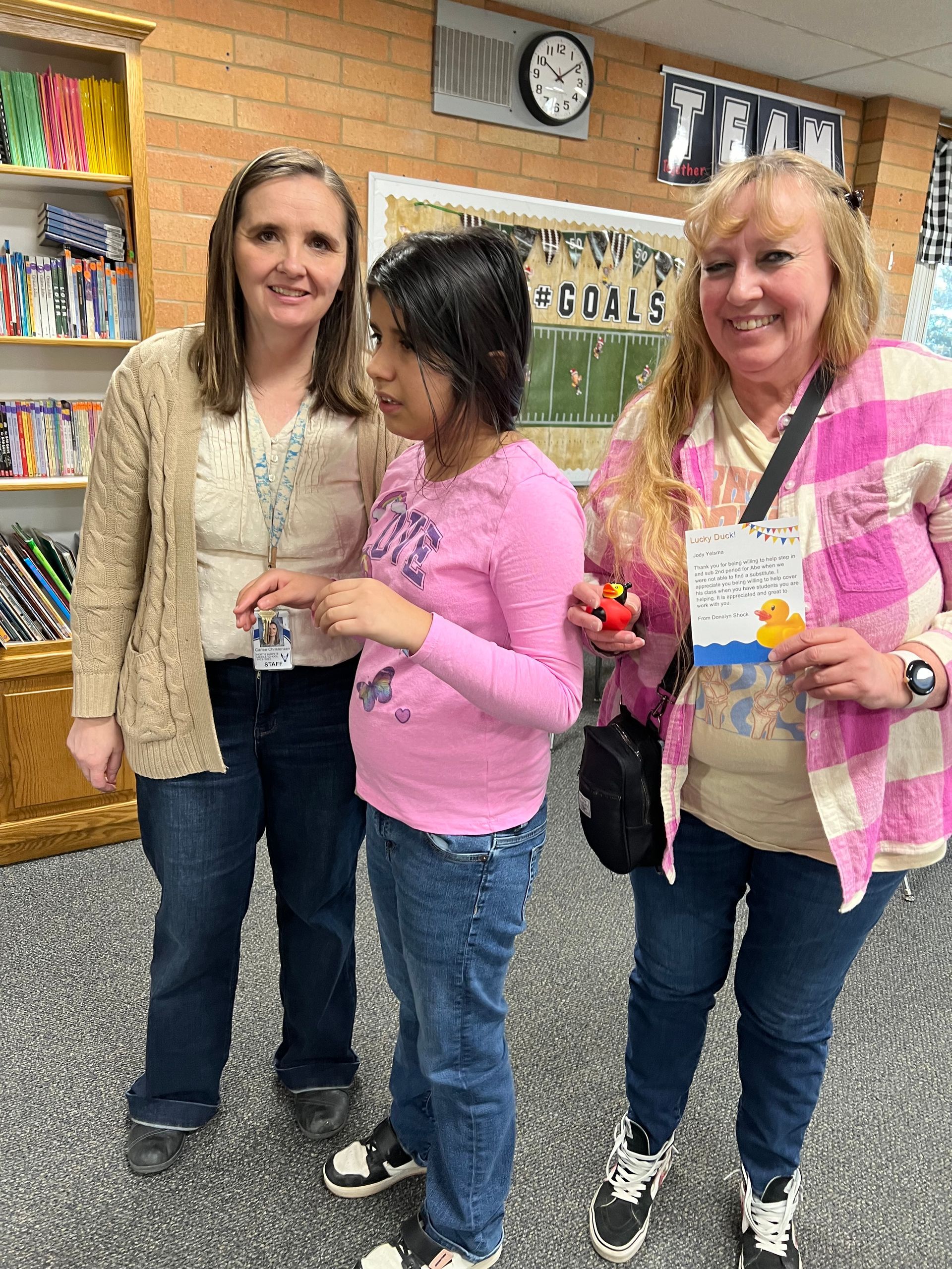 Three women are posing for a picture with a little girl in a pink shirt.