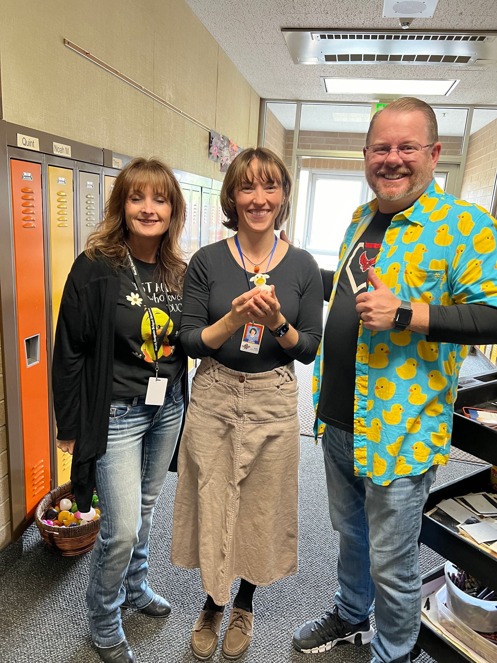 Three people are standing next to each other in a hallway.