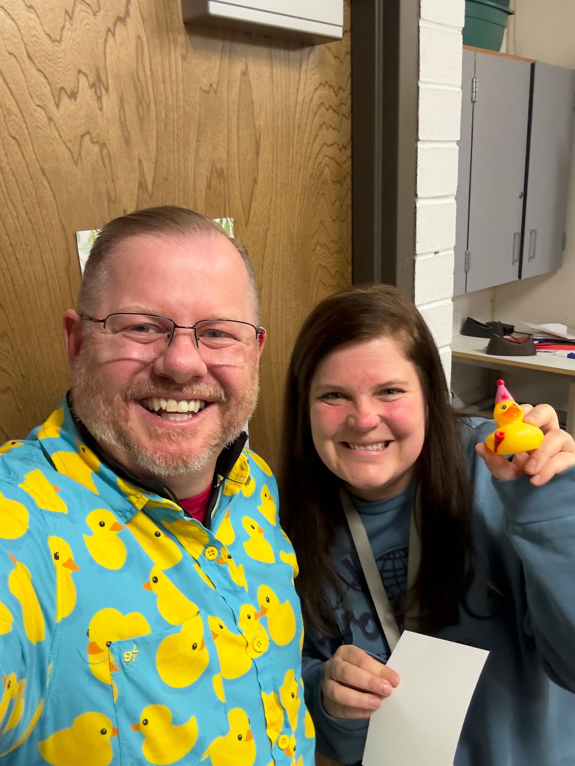 A man and a woman are posing for a picture and the woman is holding a rubber duck.