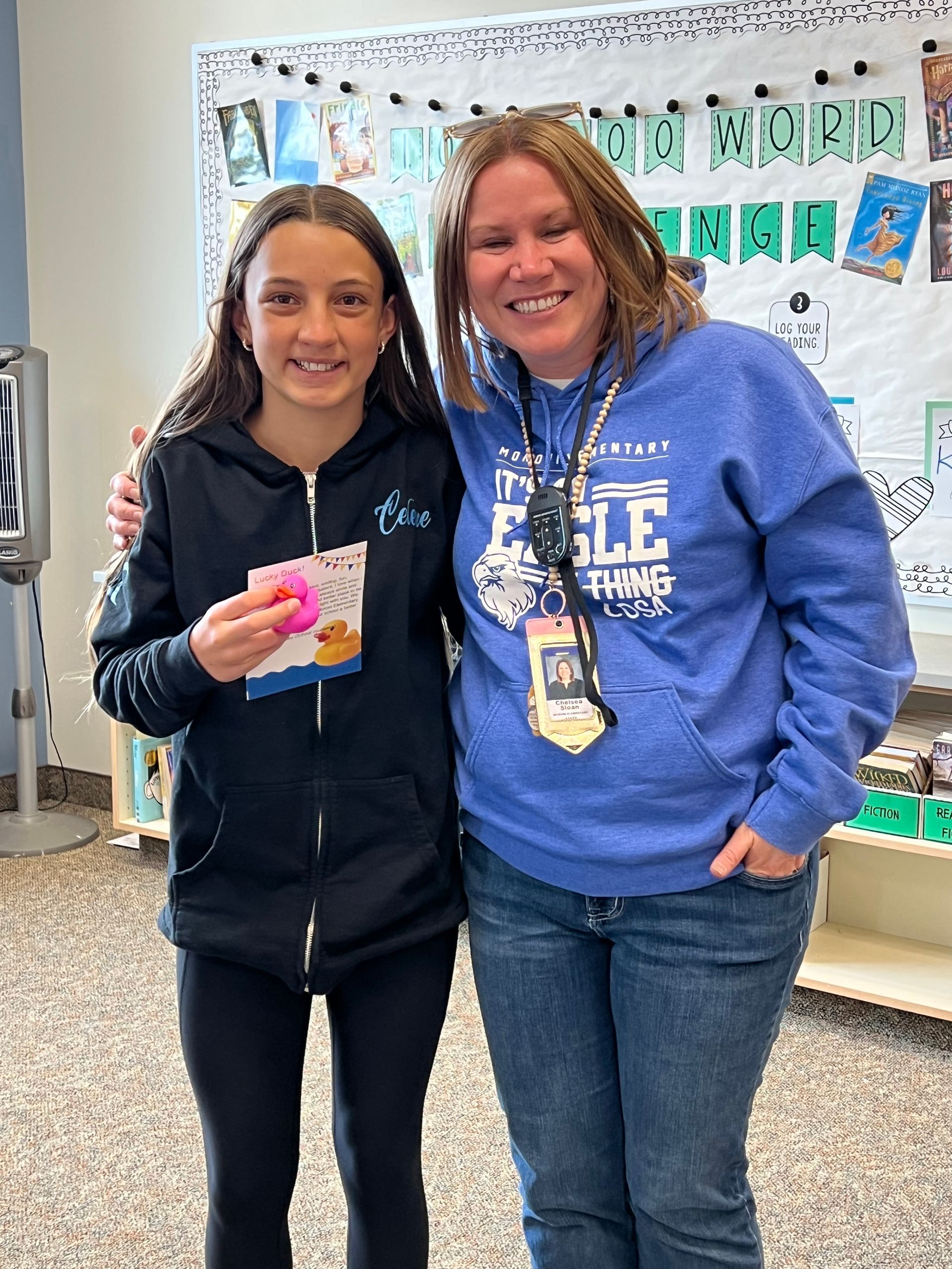 A teacher and a student are posing for a picture in a classroom.