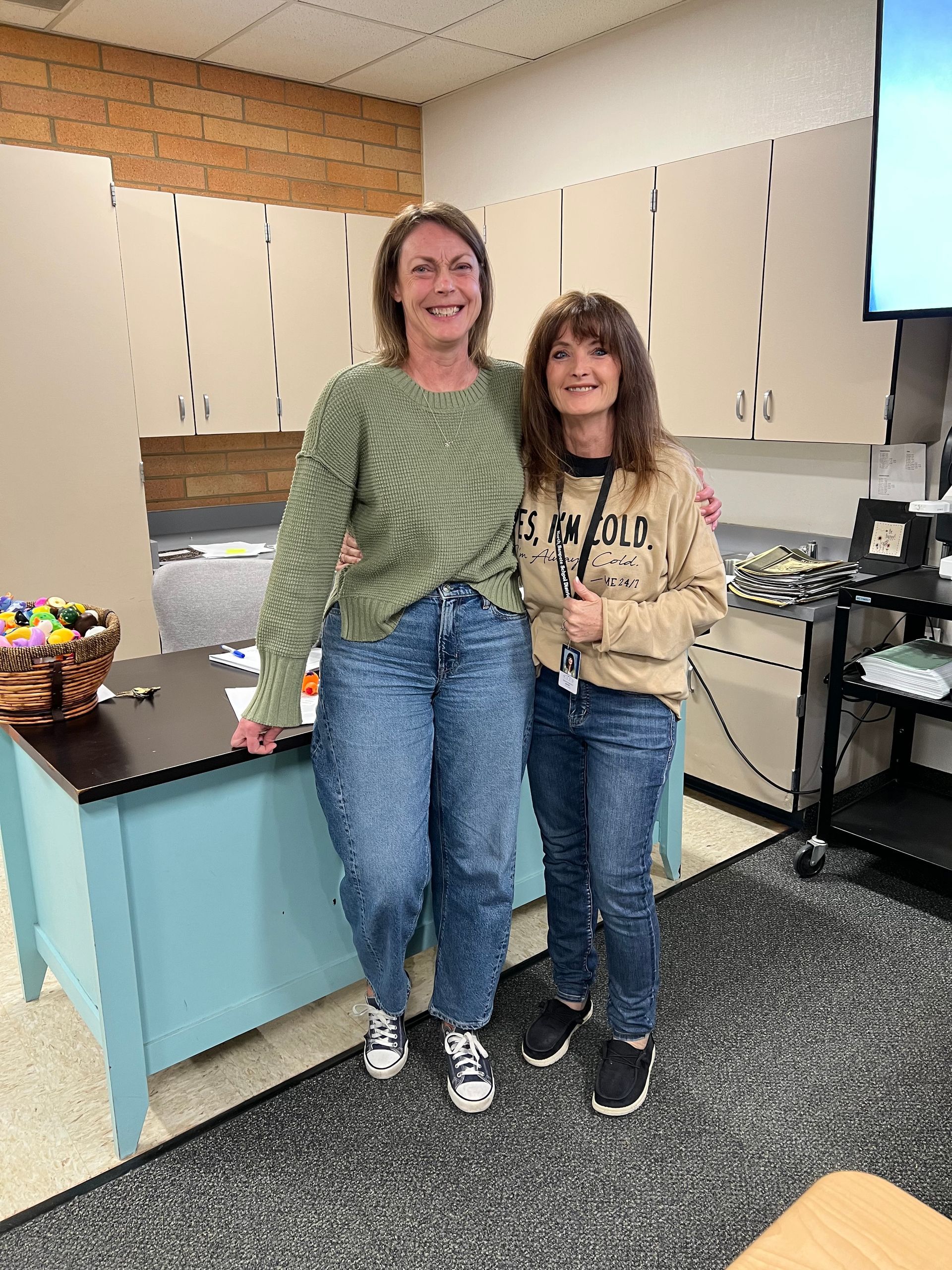 Two women are standing next to each other in a classroom.