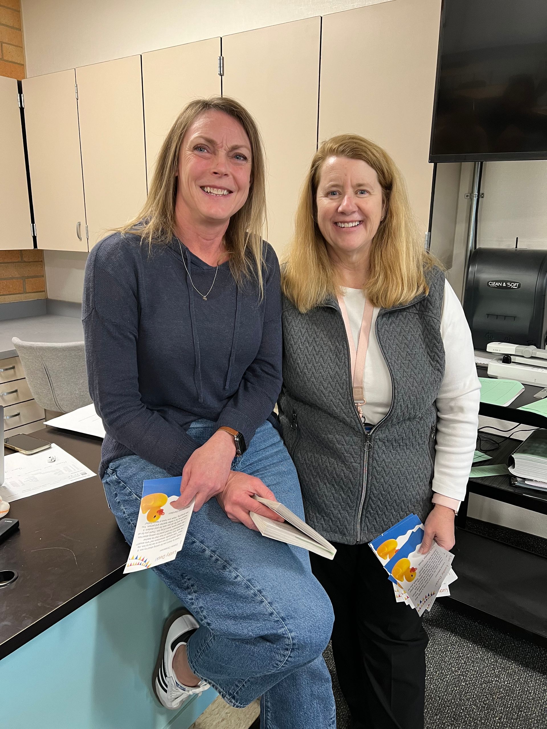 Two women are posing for a picture while sitting on a counter.