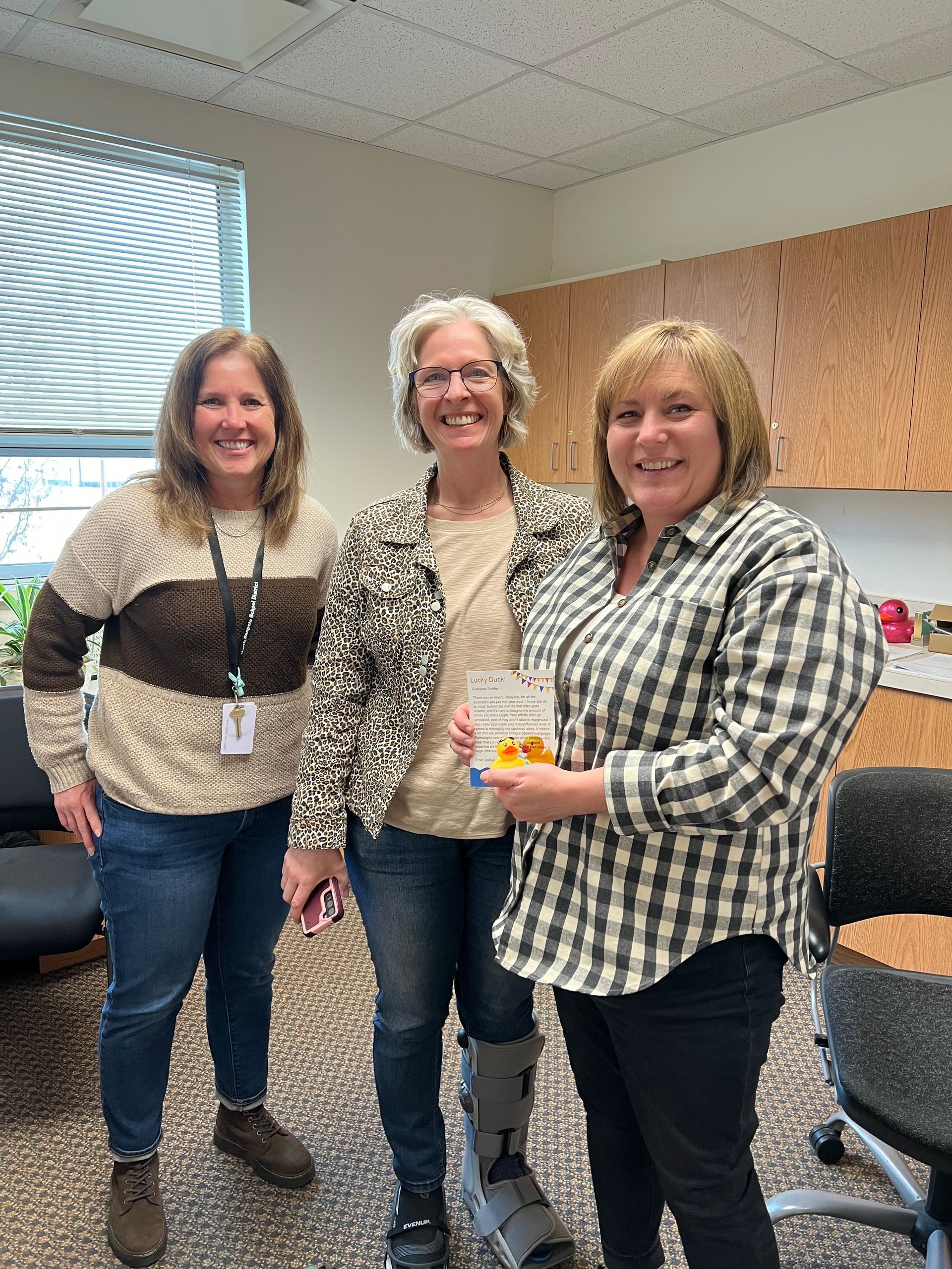 Three women are standing next to each other in a room holding a book.