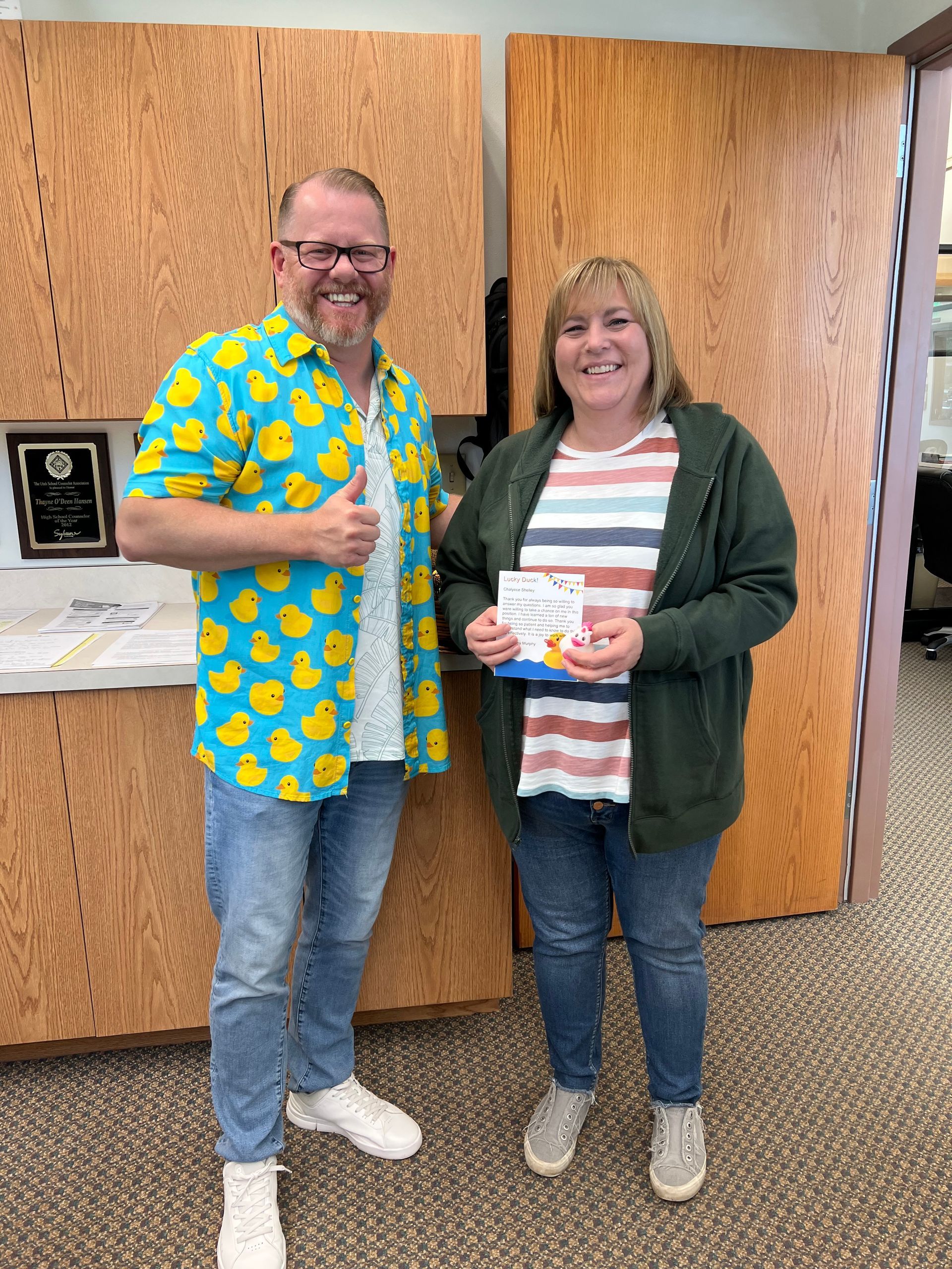 A man in a duck shirt is standing next to a woman in a striped shirt.
