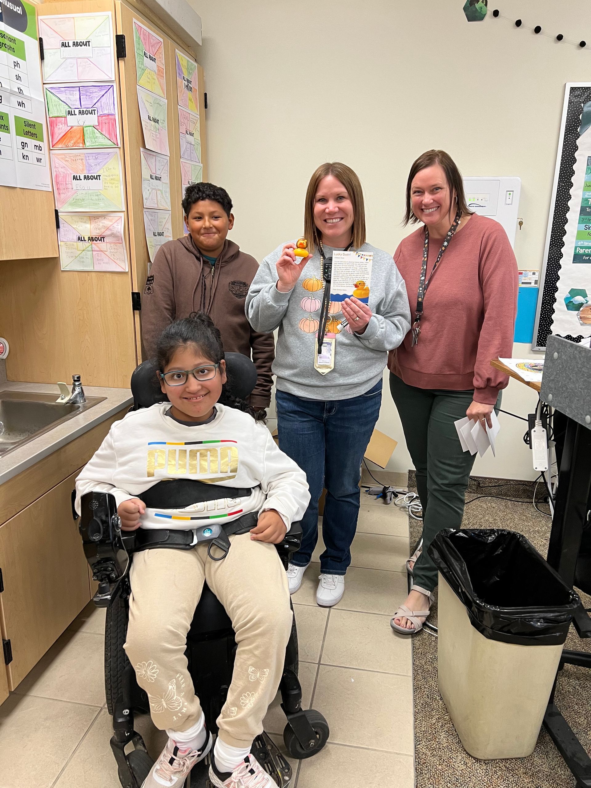 A group of people are standing around a girl in a wheelchair.