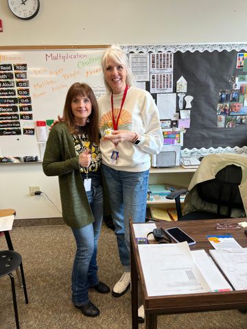 Two women are standing next to each other in a classroom.